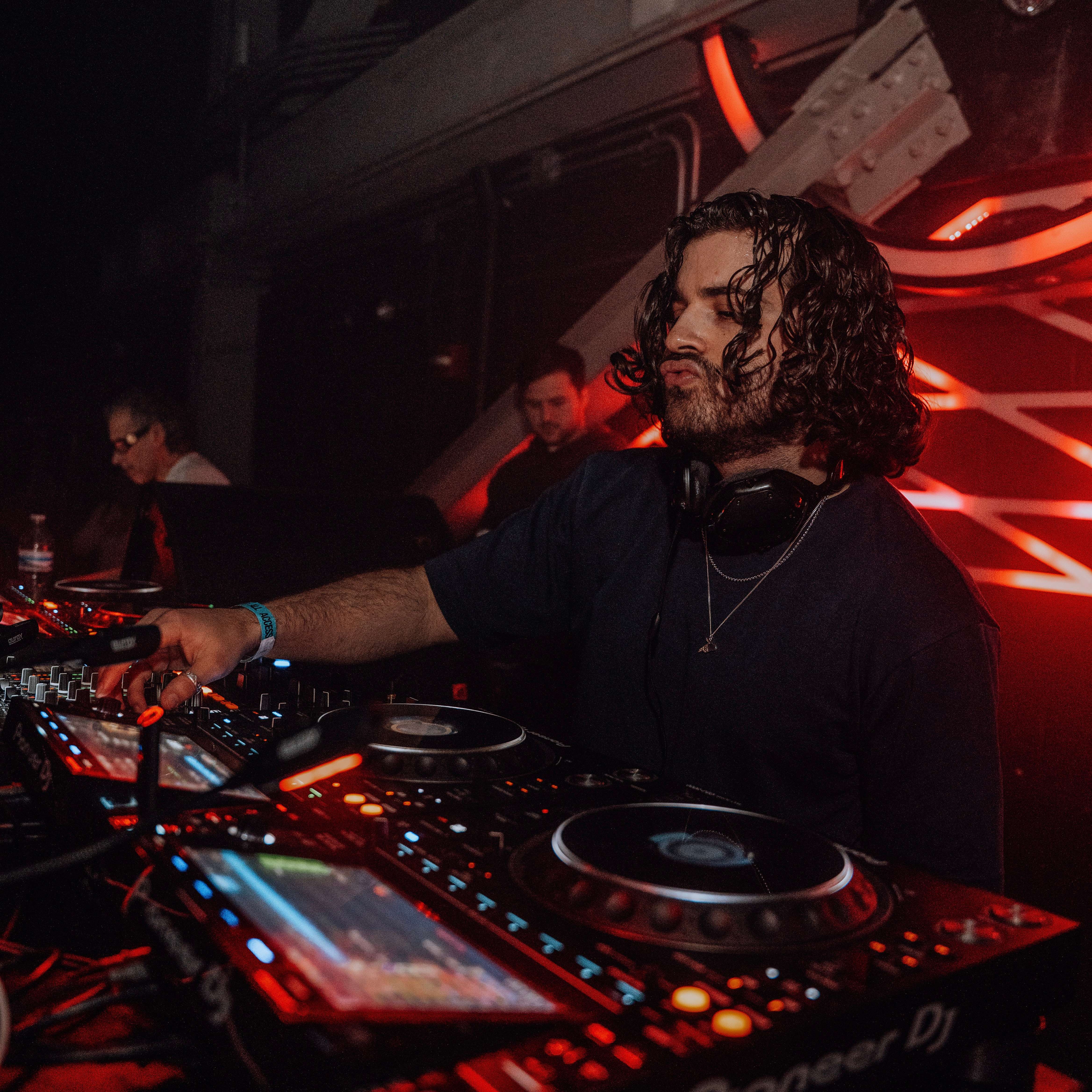 a man with long hair is djing at a nightclub