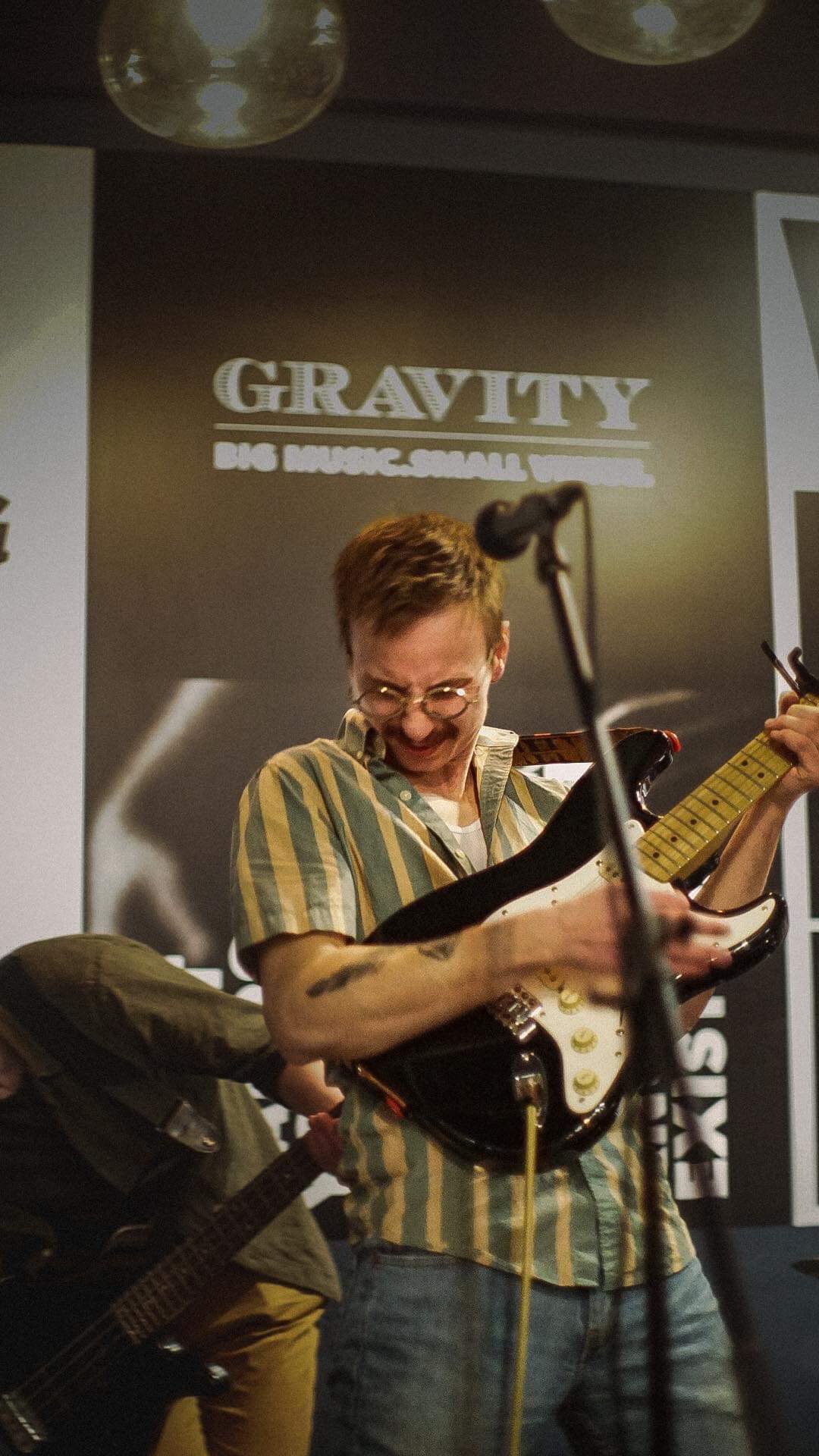 a man playing a guitar in front of a microphone