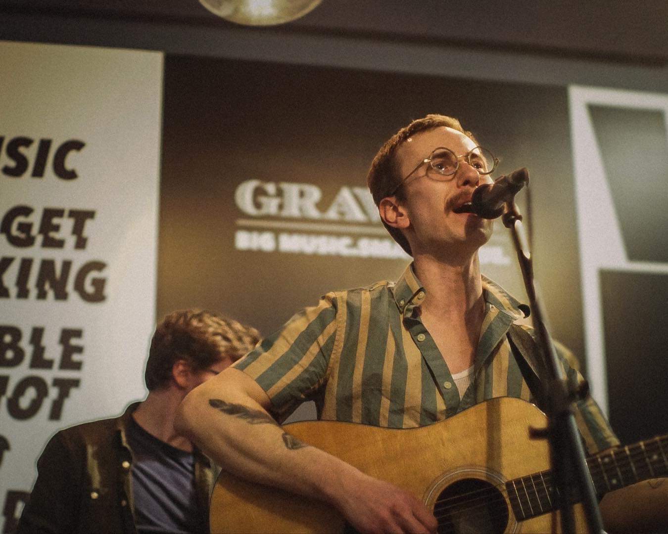 a man singing and playing an acoustic guitar in front of a microphone
