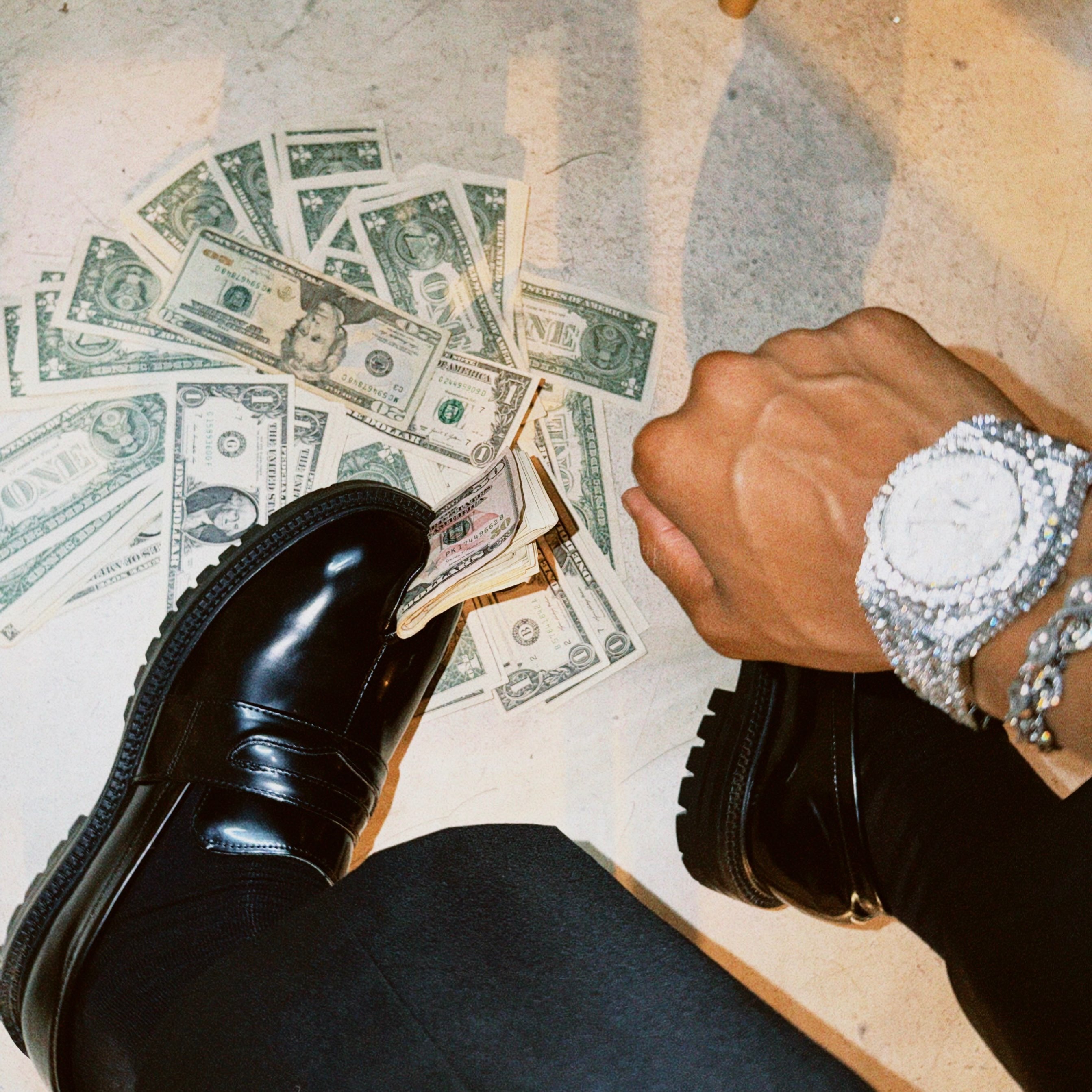 Don Juano - LEVELS: a man sitting on the floor with money on his feet
