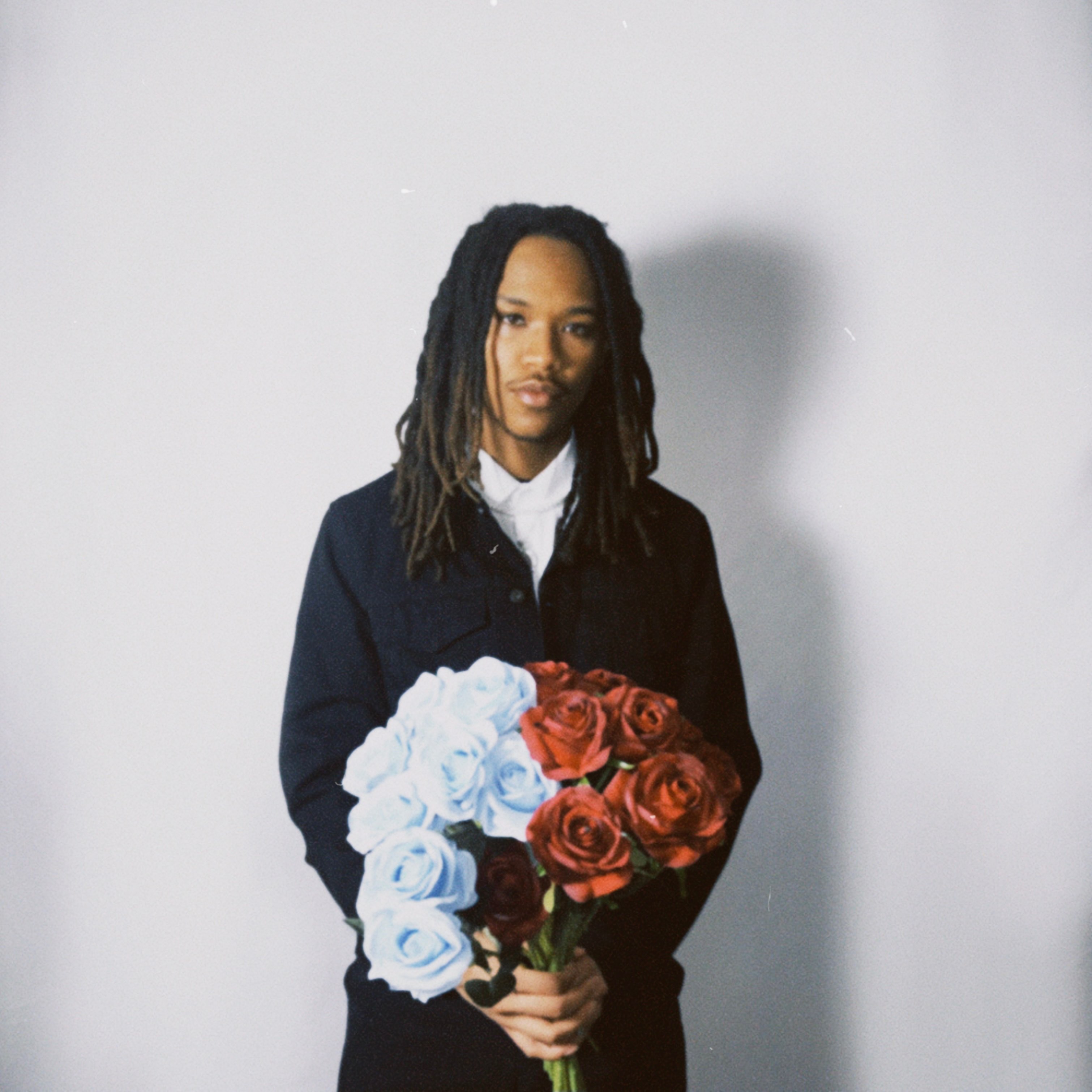 a man with dreadlocks holding a bouquet of flowers