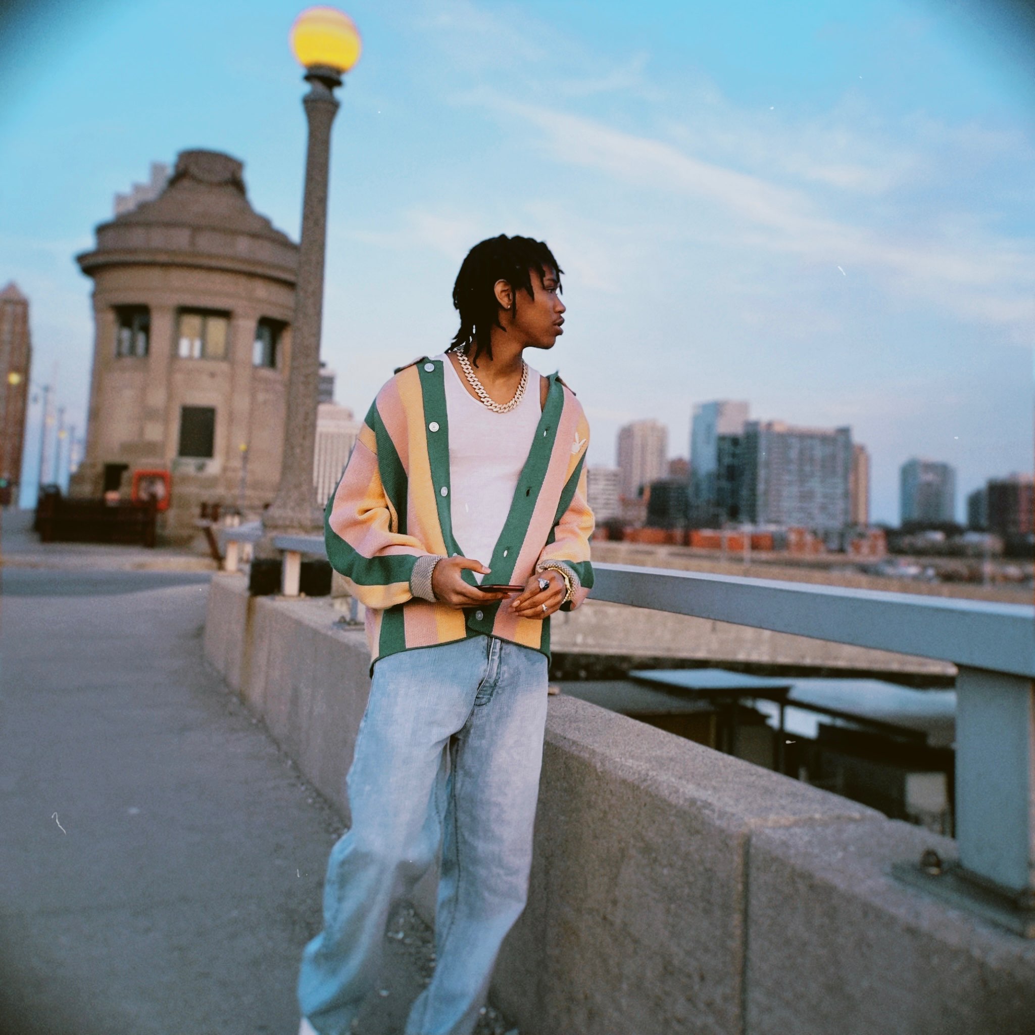a young man standing on a bridge with a city in the background