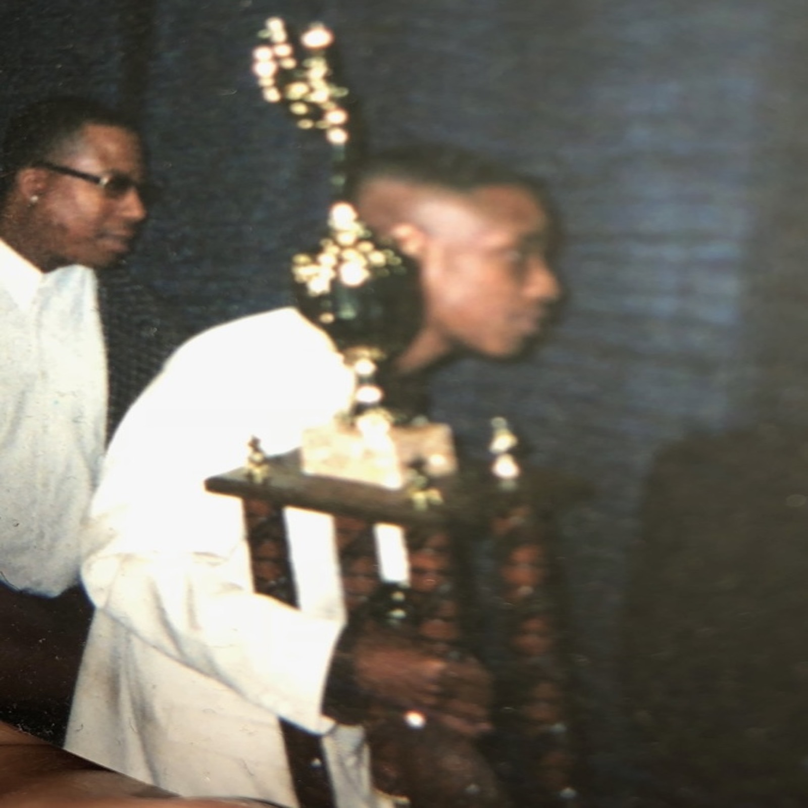 two men standing next to each other holding trophies