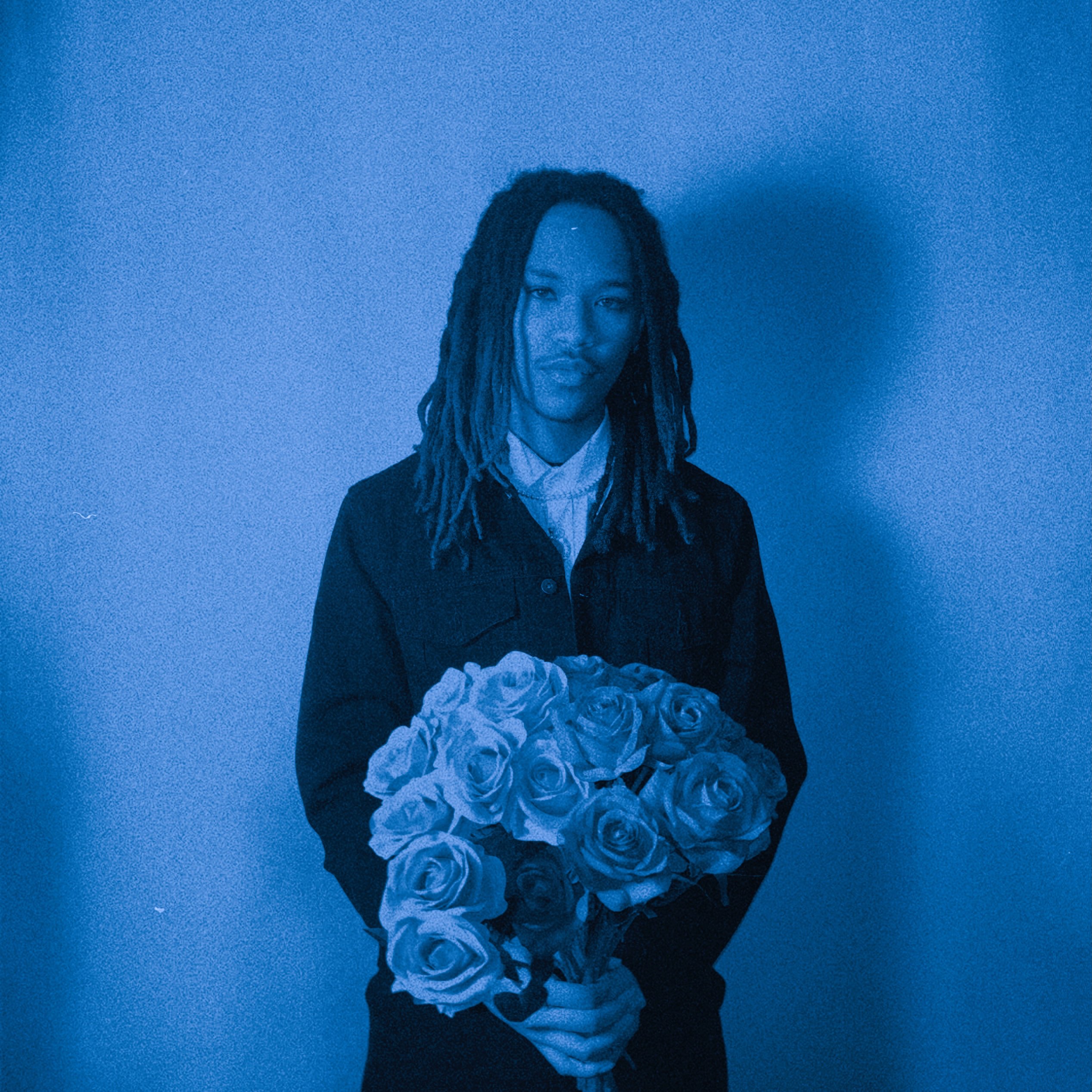 a man with dreadlocks holding a bouquet of roses