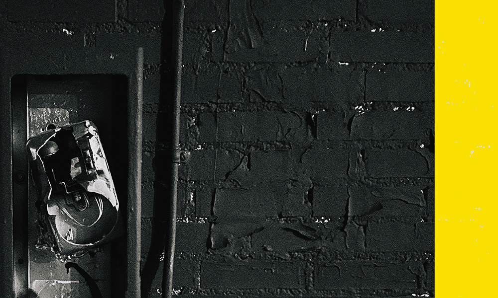 a black and yellow photo of a parked car next to a brick wall
