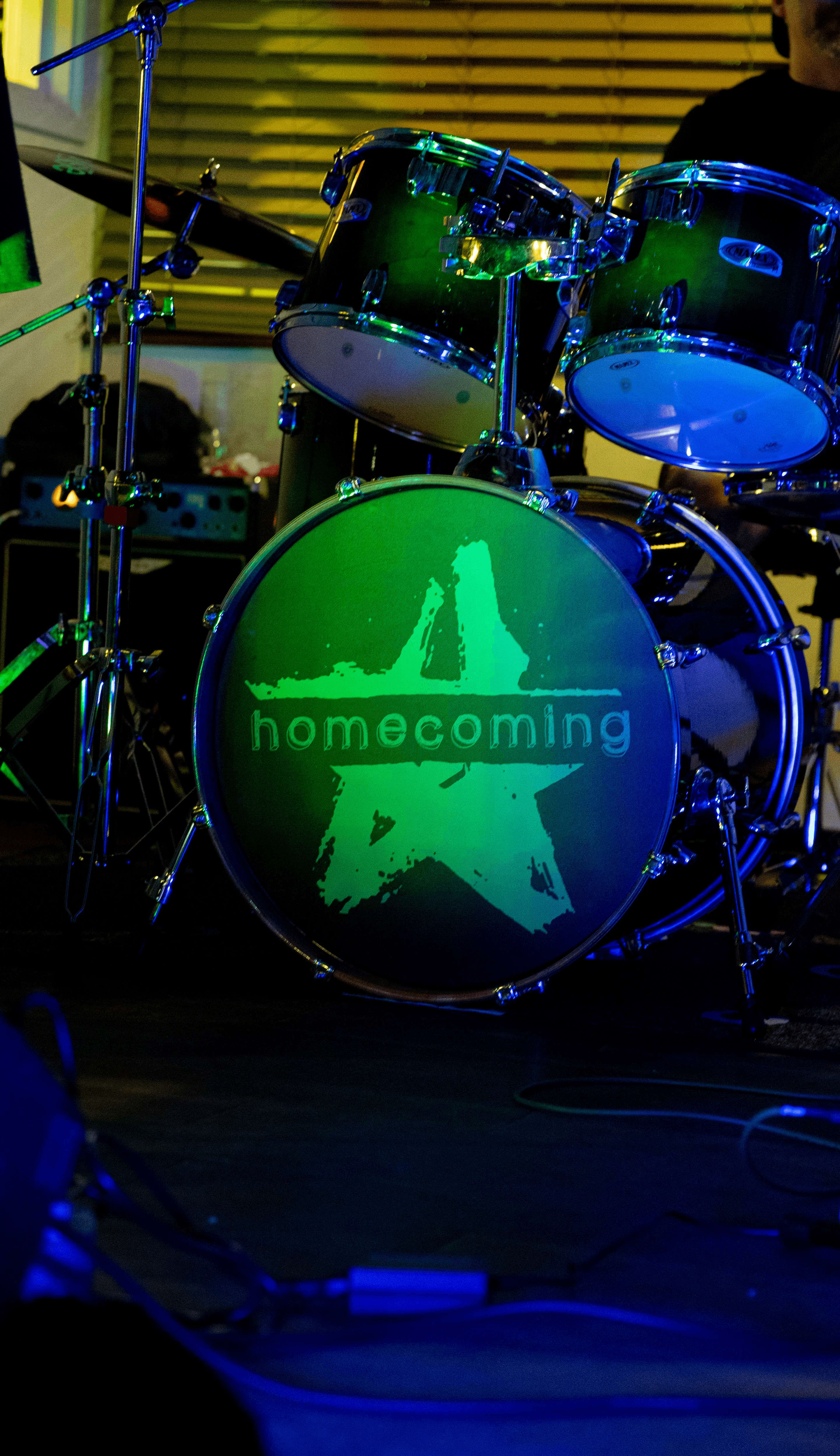 a man playing drums in front of a homecoming sign