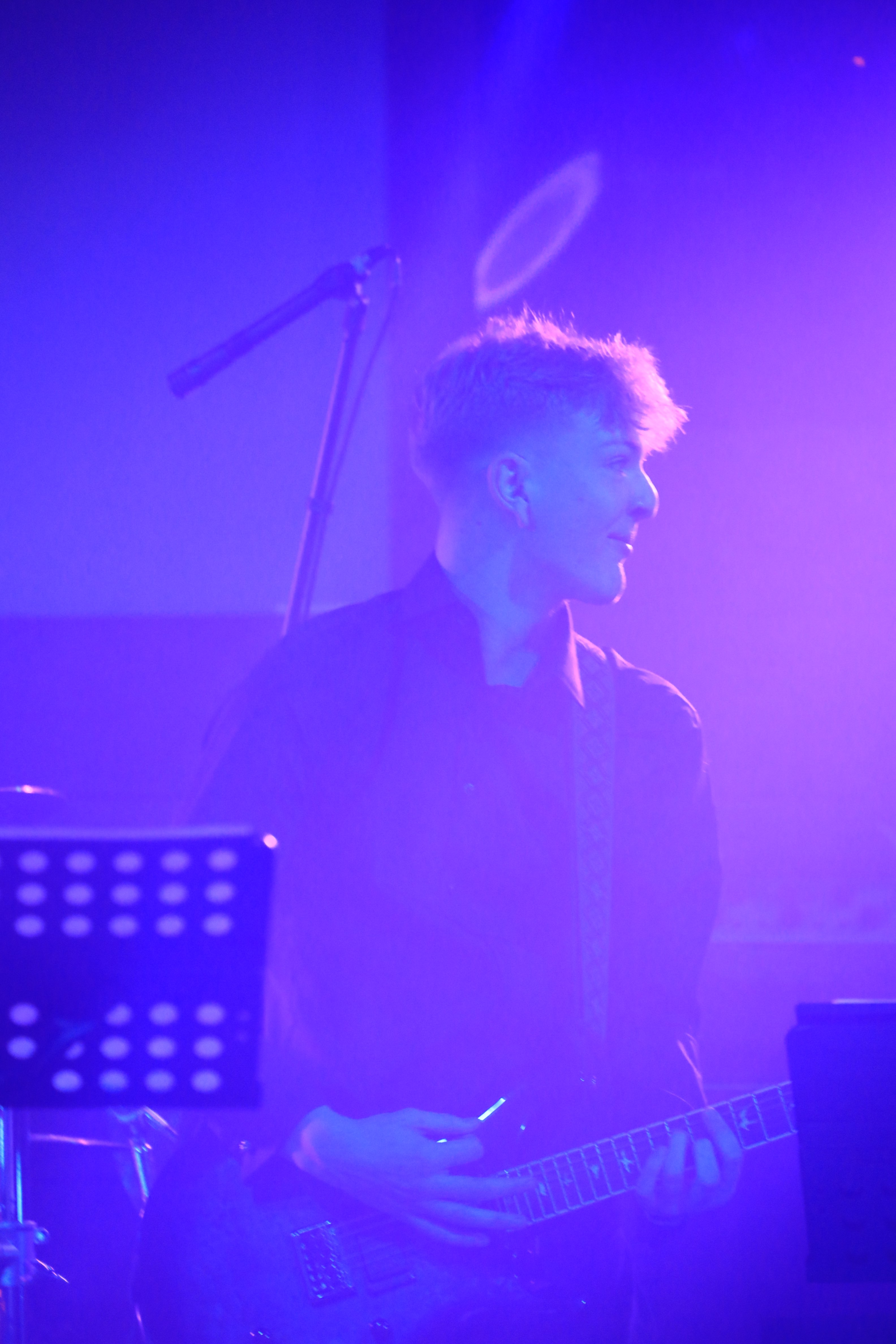 a man playing a guitar in front of a purple light