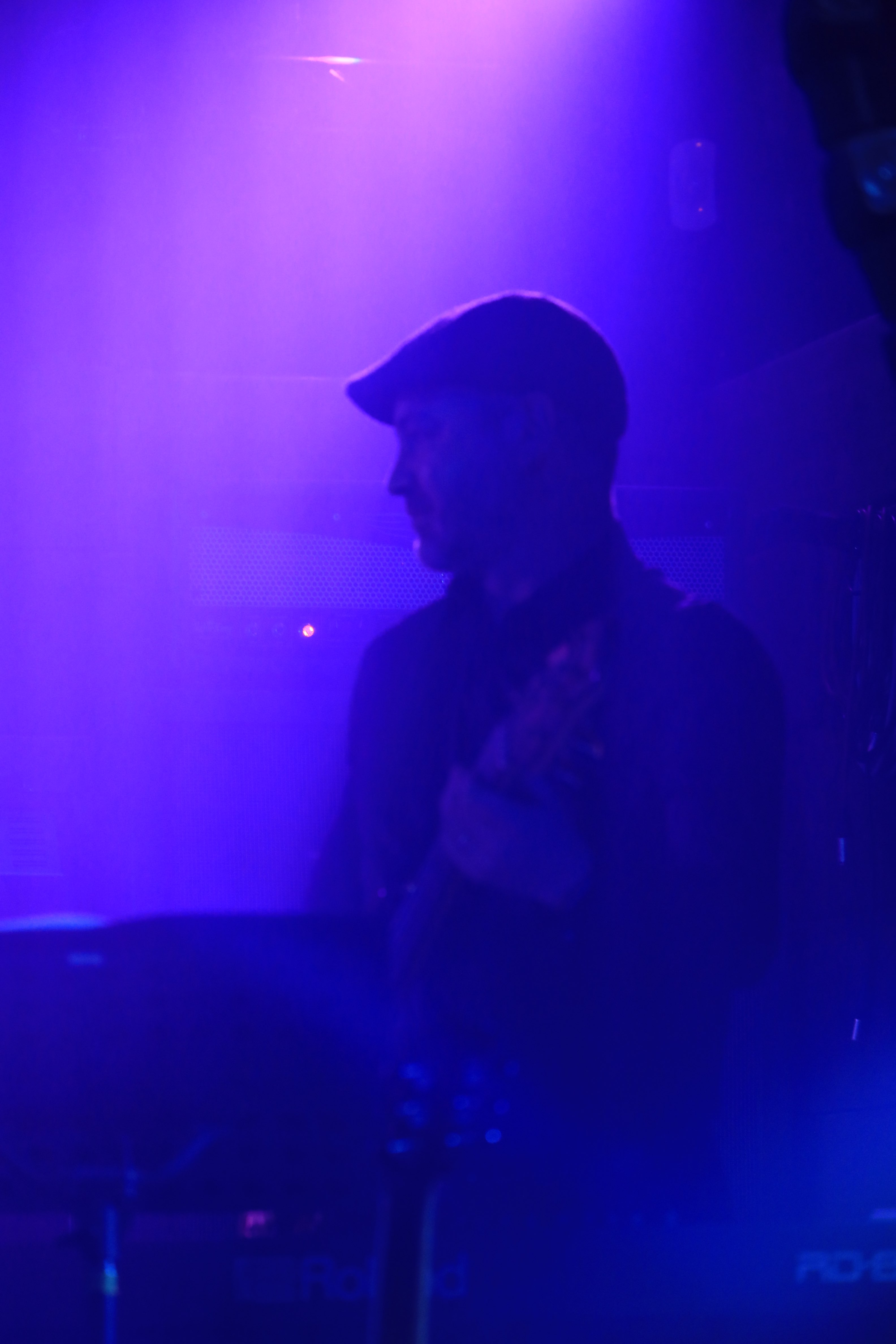 a man in a hat standing in front of a purple light