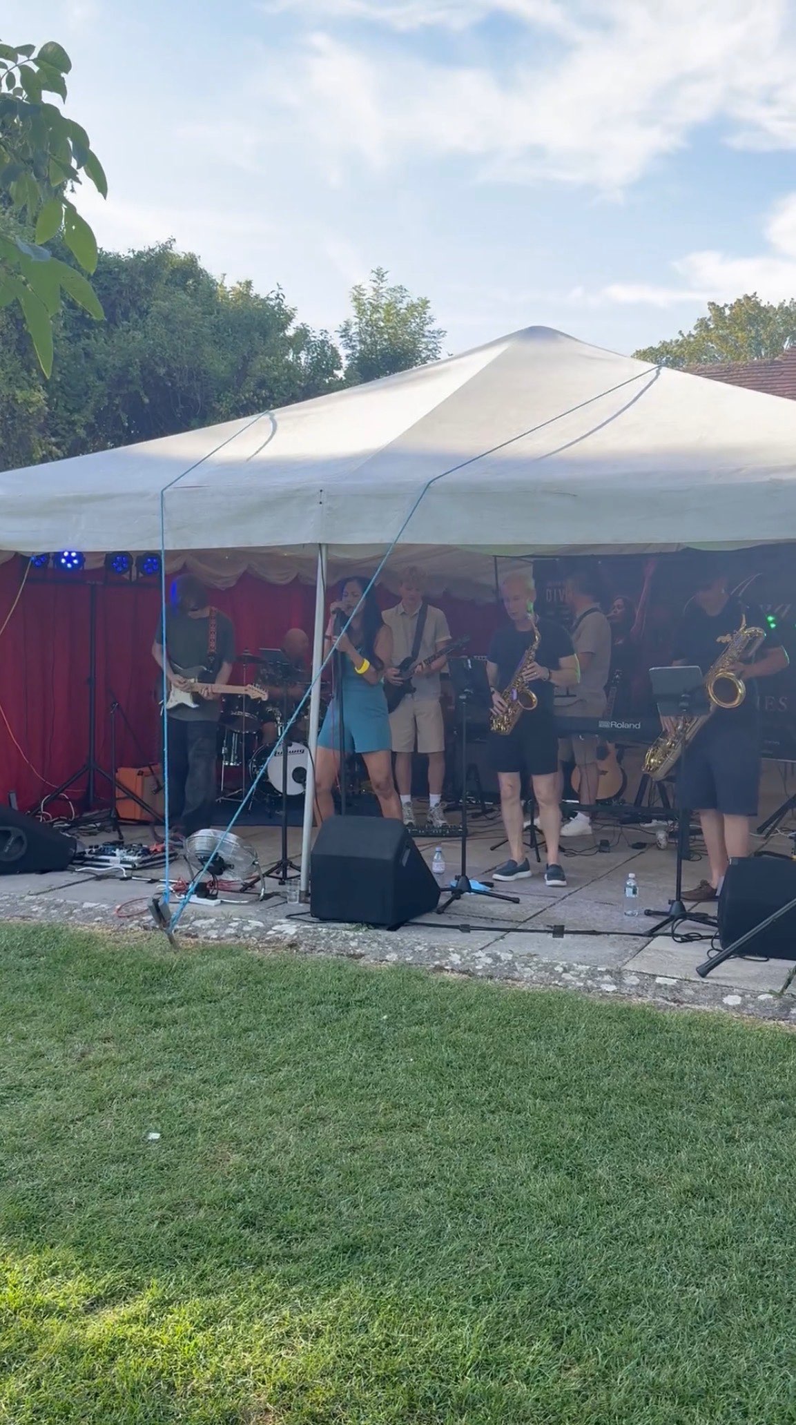 a band performs under a tent in a yard