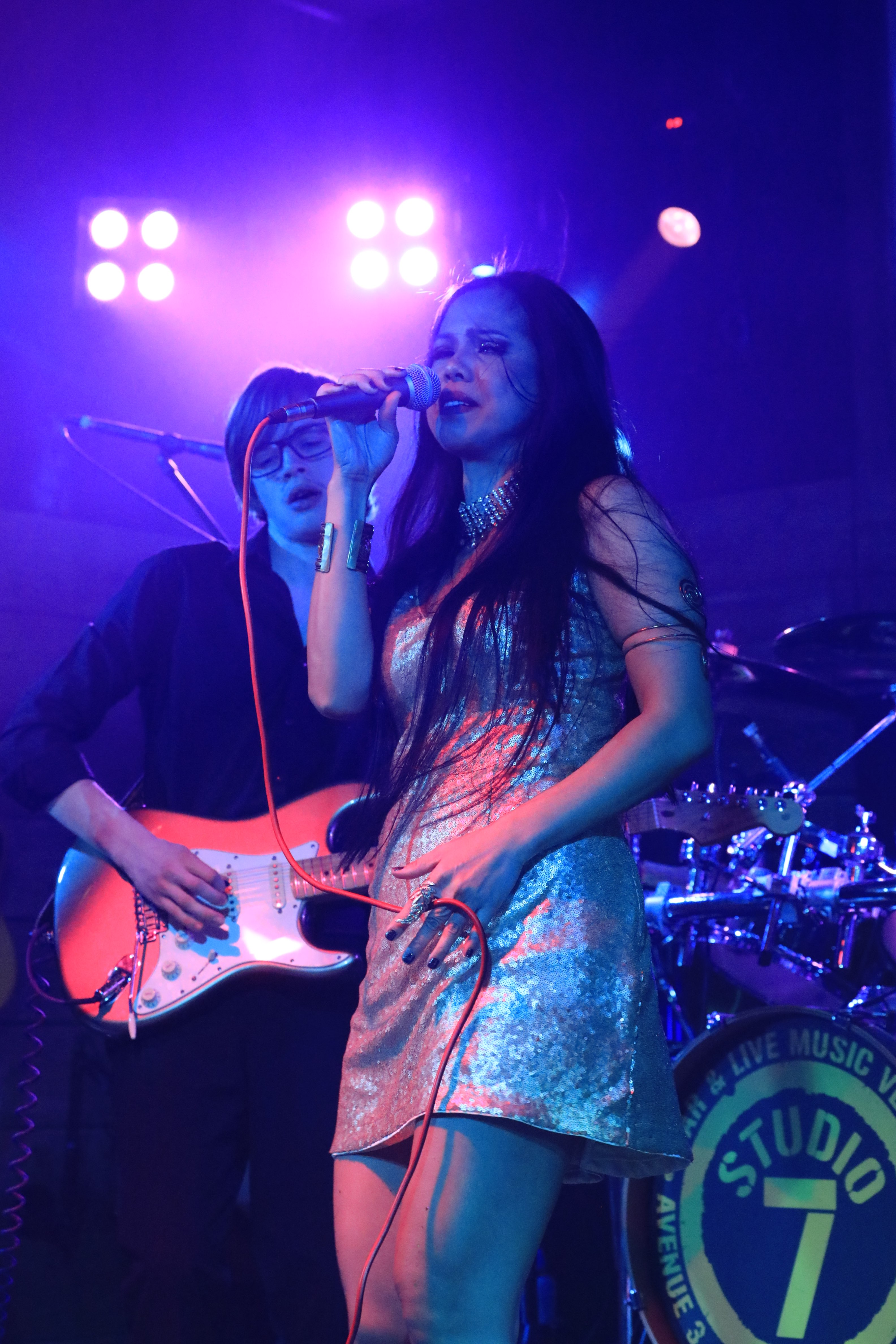a woman in a silver dress singing into a microphone