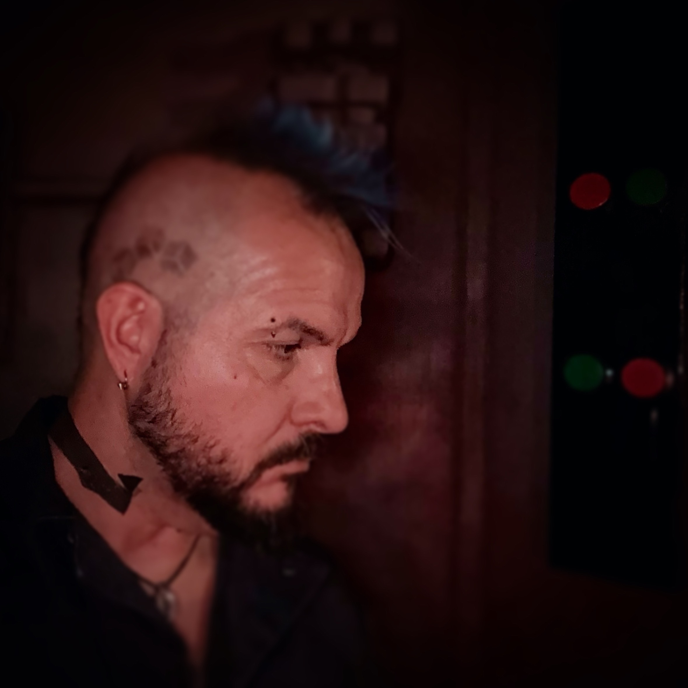 a man with a blue mohawk and tattoos in a dark room