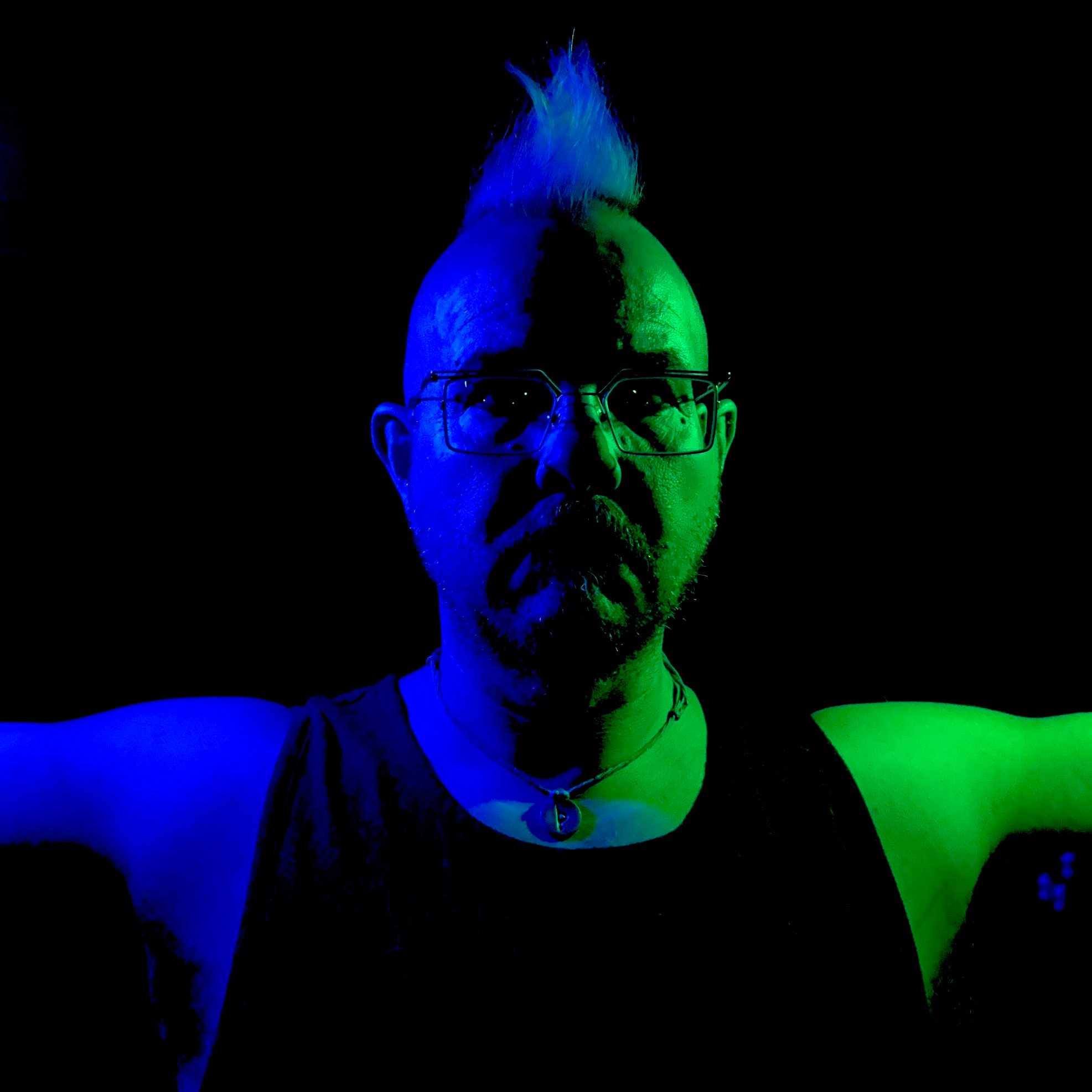 a man with a green mohawk in front of a black background
