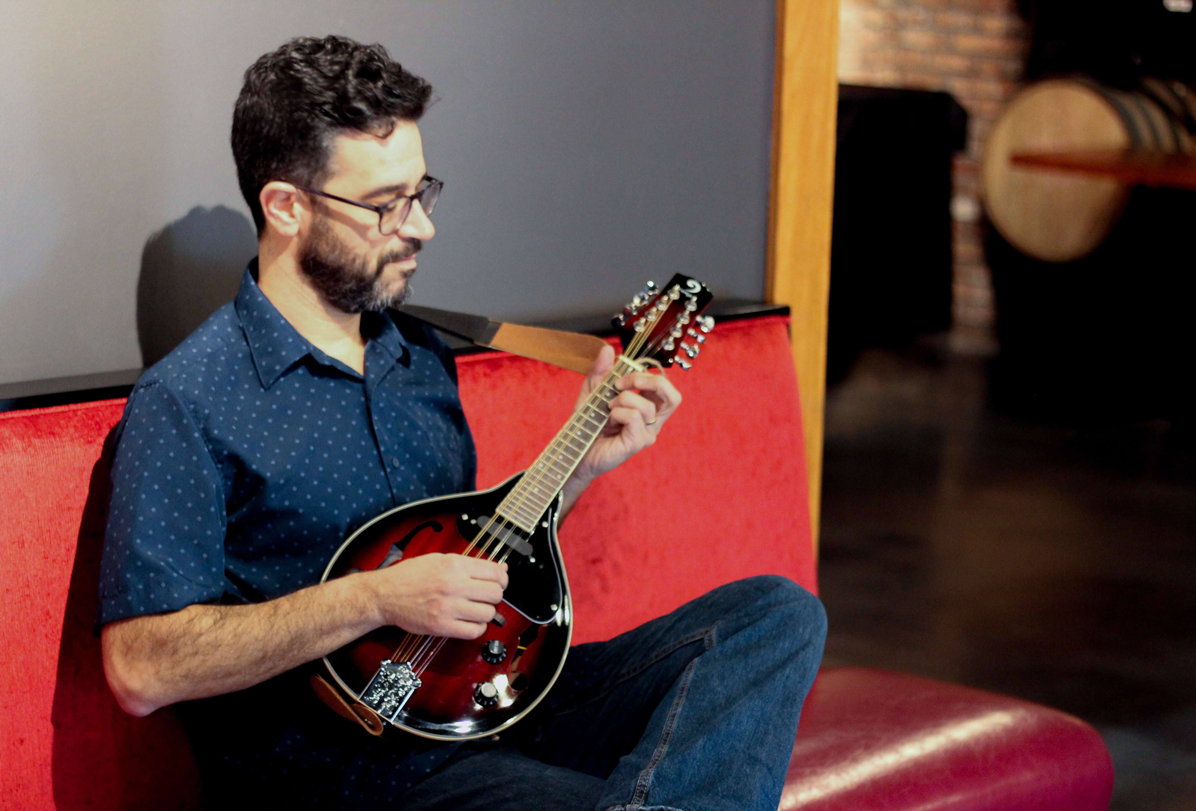 a man sitting on a red couch playing a mandolin