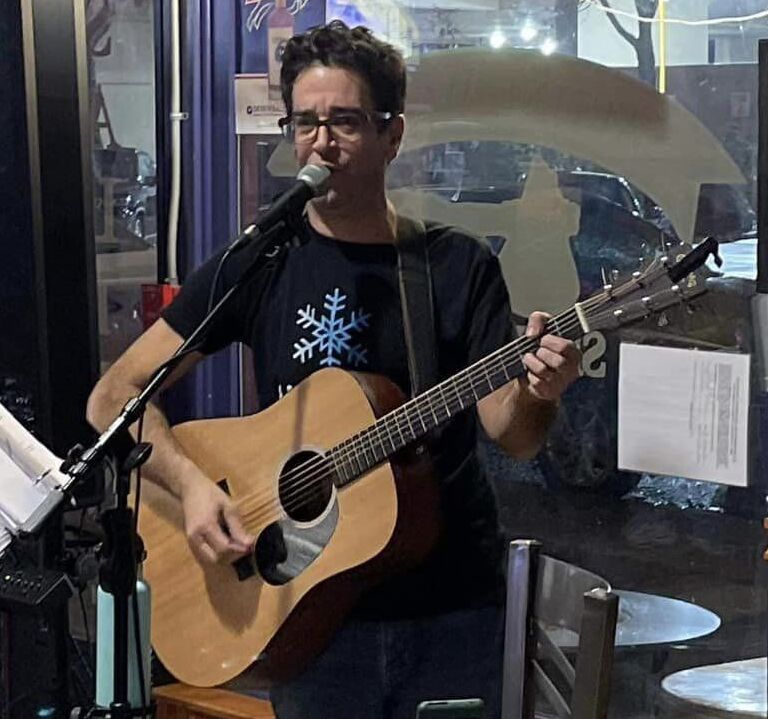 a man playing an acoustic guitar in front of a microphone