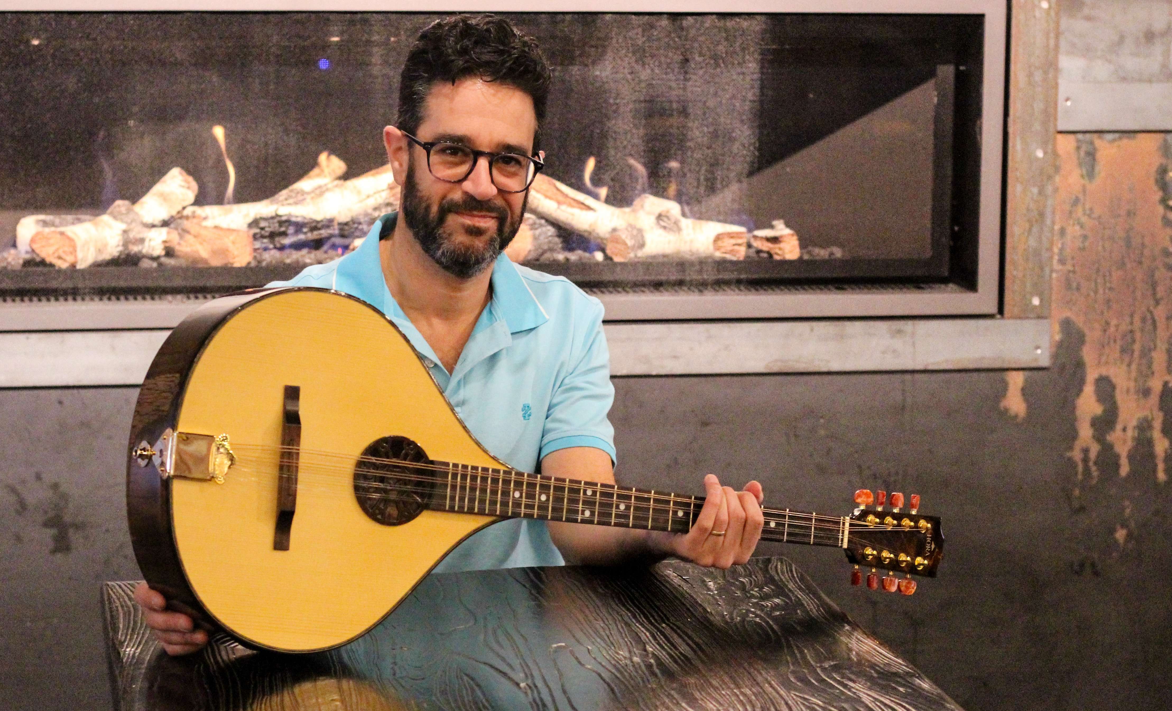 a man holding a mandolin in front of a fireplace