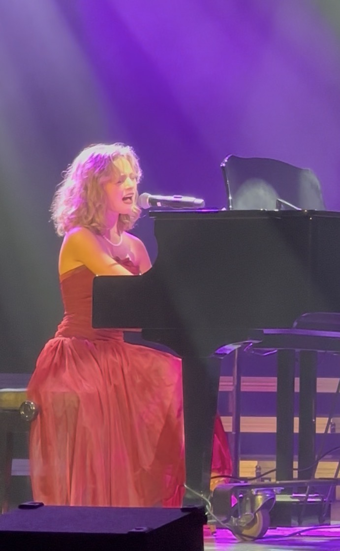 a woman in a red dress playing a piano