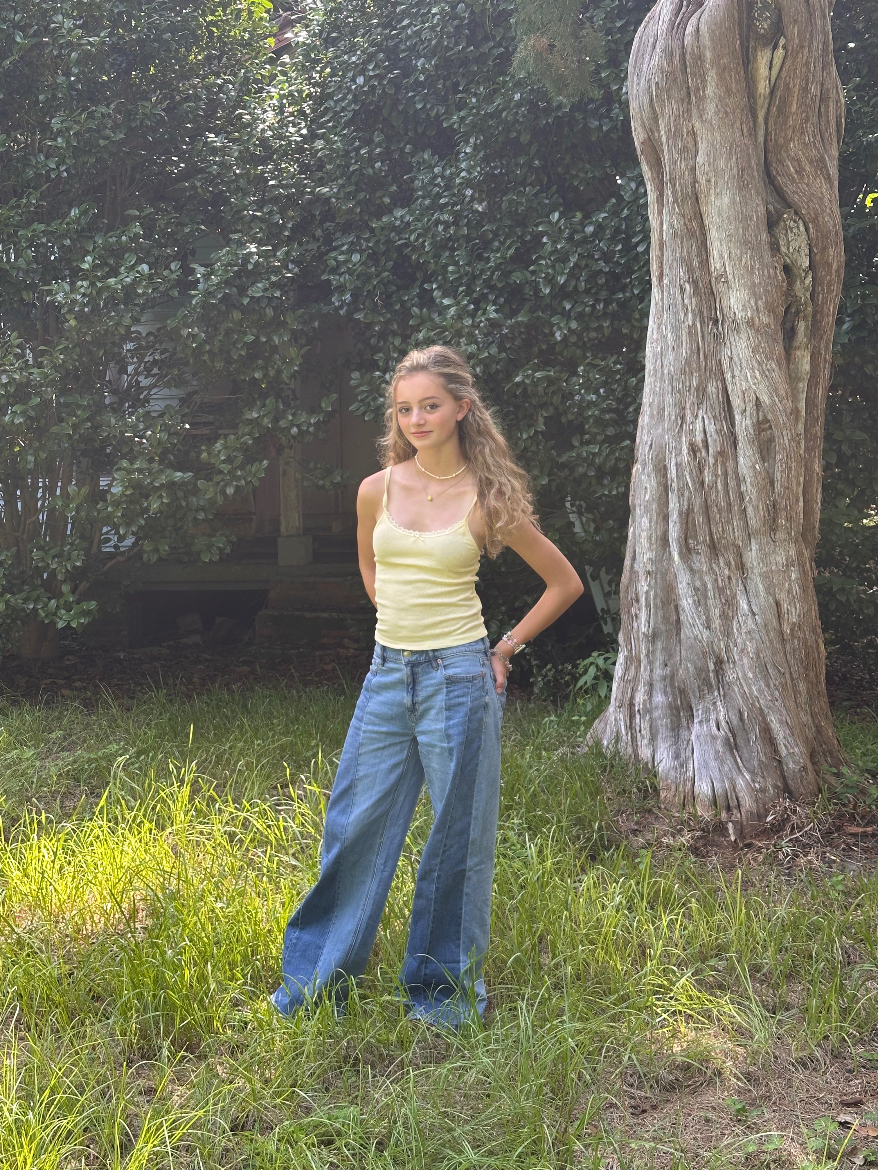 a woman standing in front of a tree in denim wide leg pants