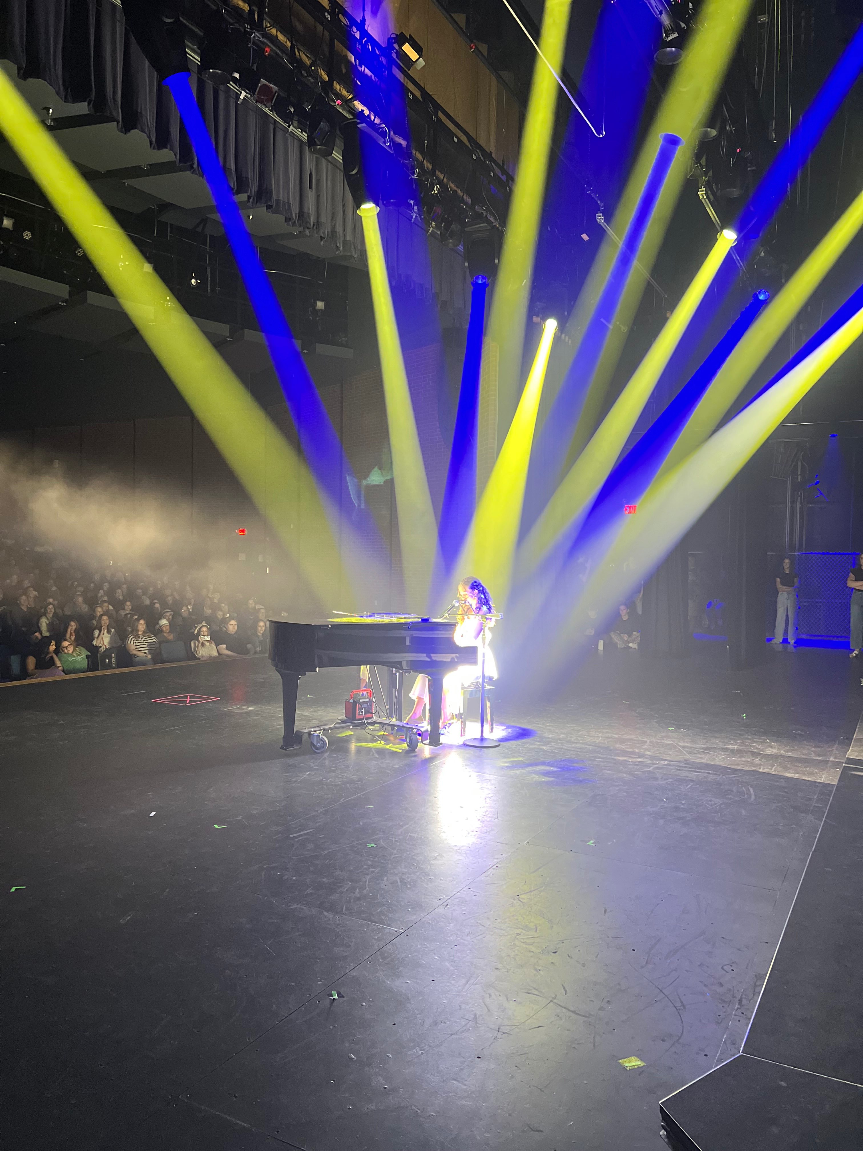 a person playing a piano in front of a stage with blue and yellow lights