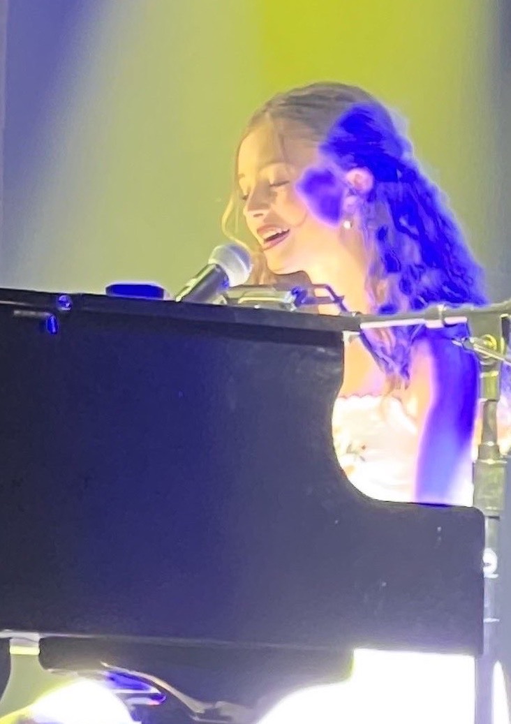 a young girl playing a piano in front of a microphone