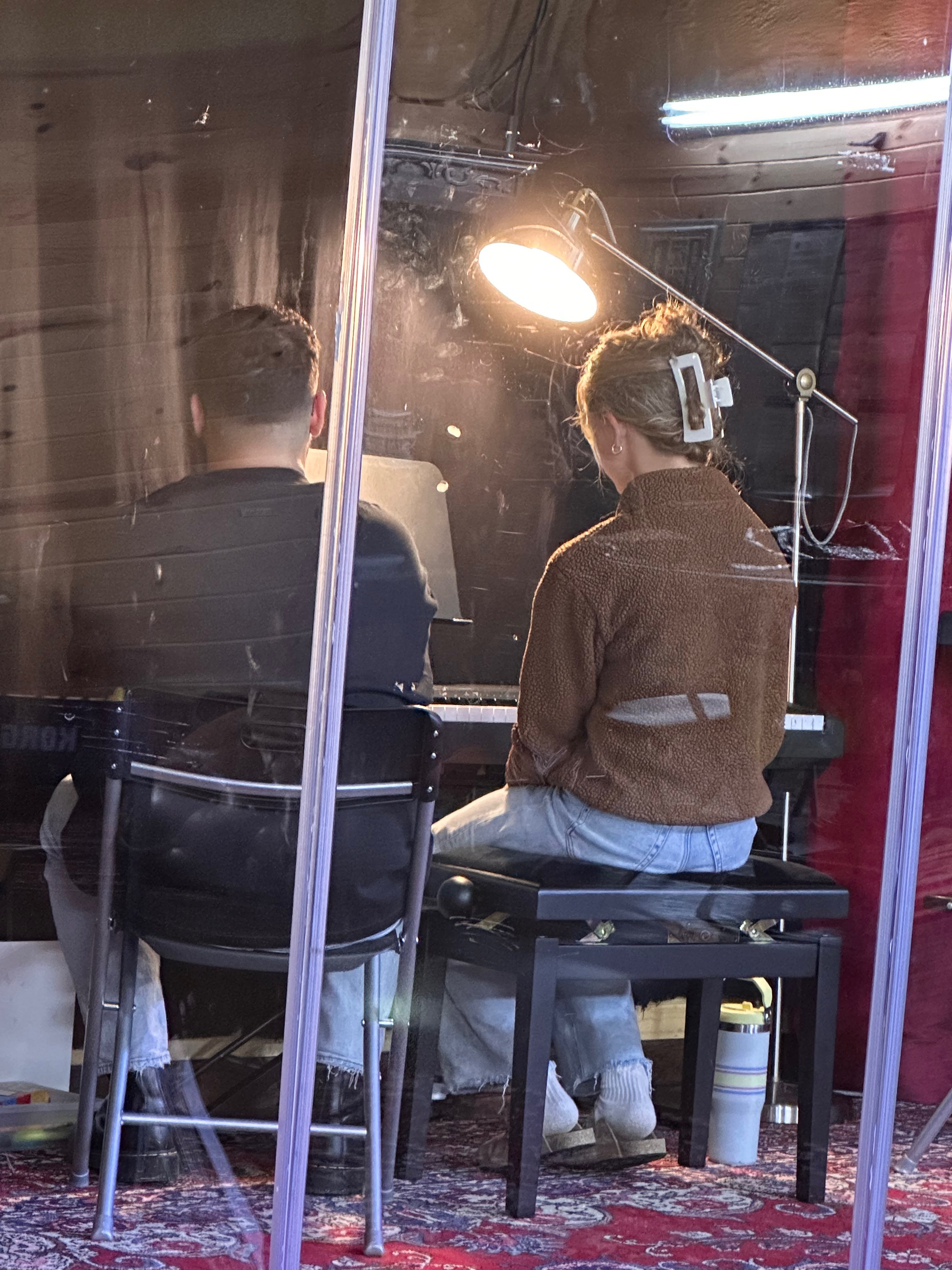 two people sitting in front of a mirror in a recording studio