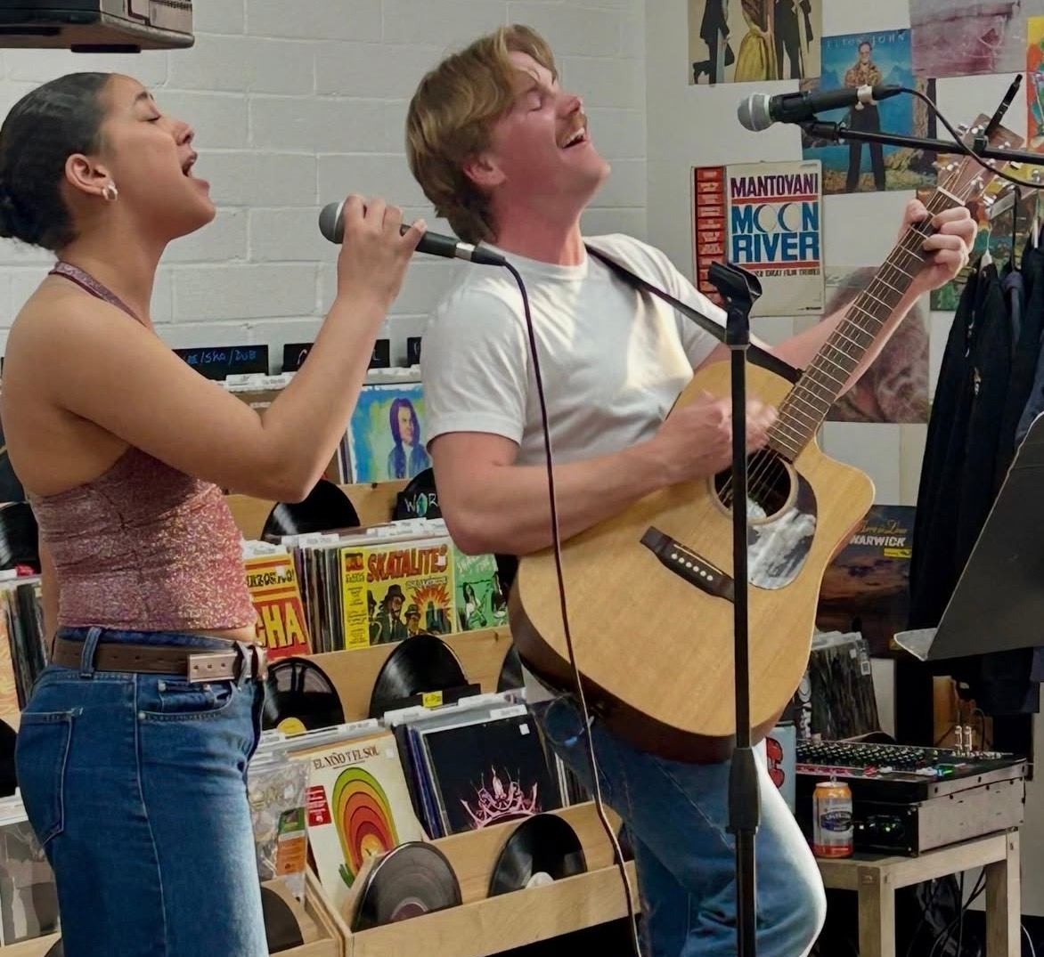 two people singing into microphones in a record store