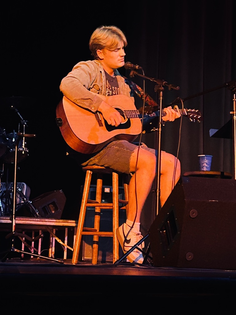 a young man playing an acoustic guitar on stage