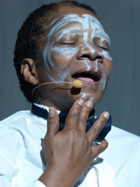 a man with white paint on his face and a bow tie