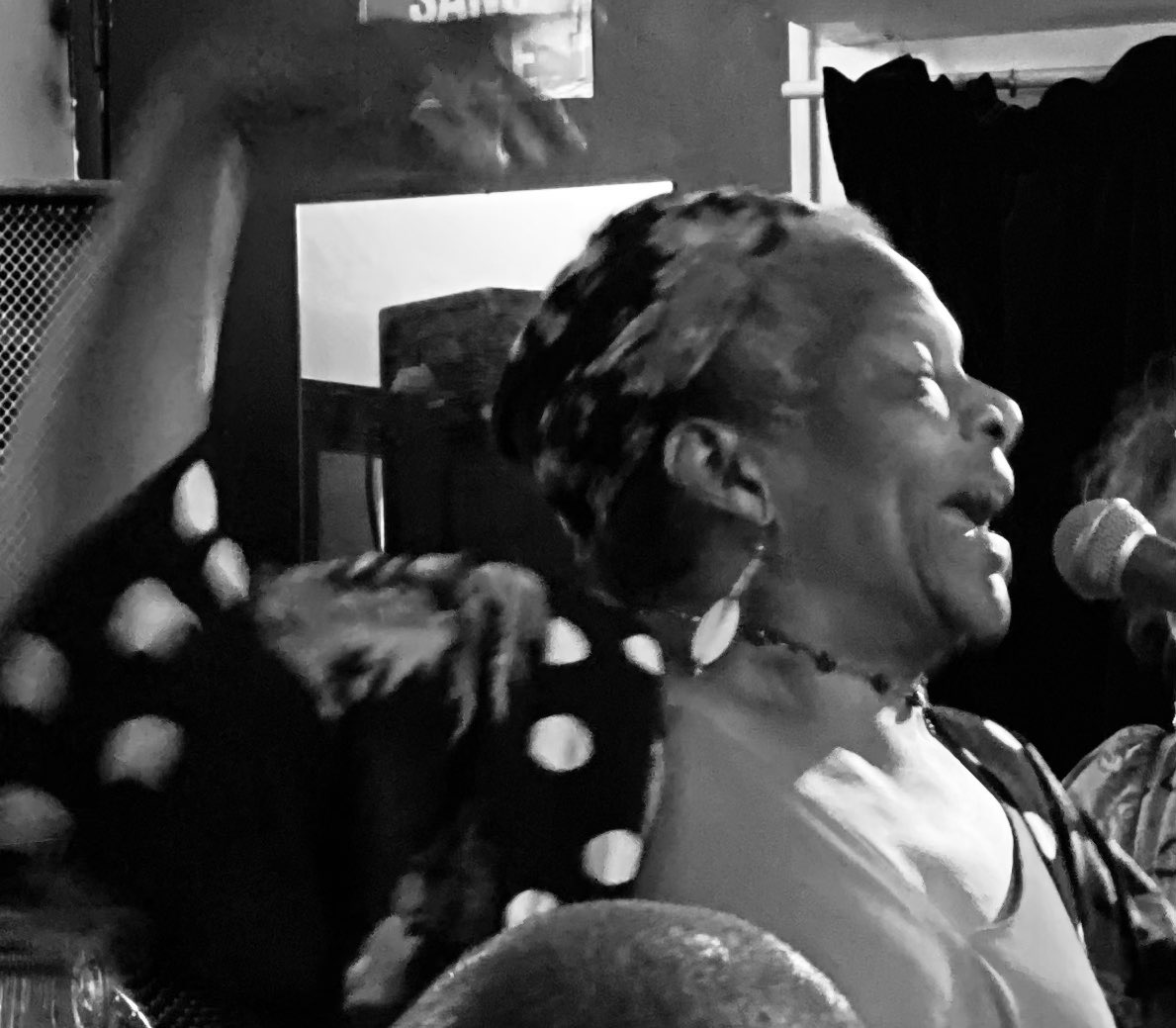 a black and white photo of a woman singing into a microphone