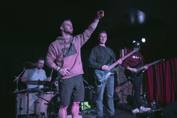 a group of people on stage with a guitar and drums