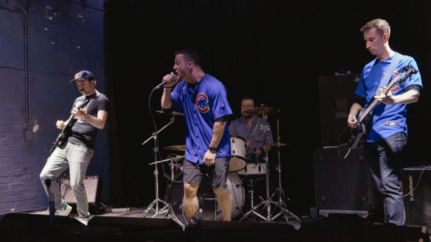 a group of men on stage with guitars and drums