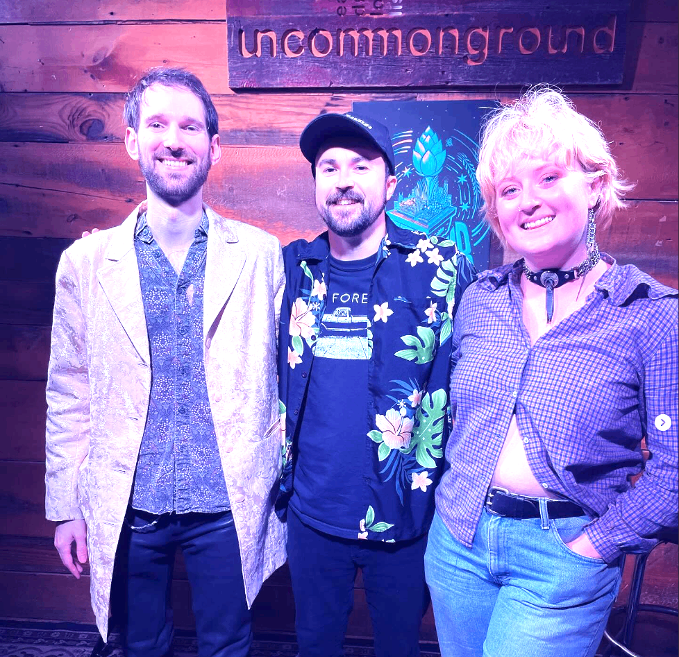 three people standing in front of a wooden wall
