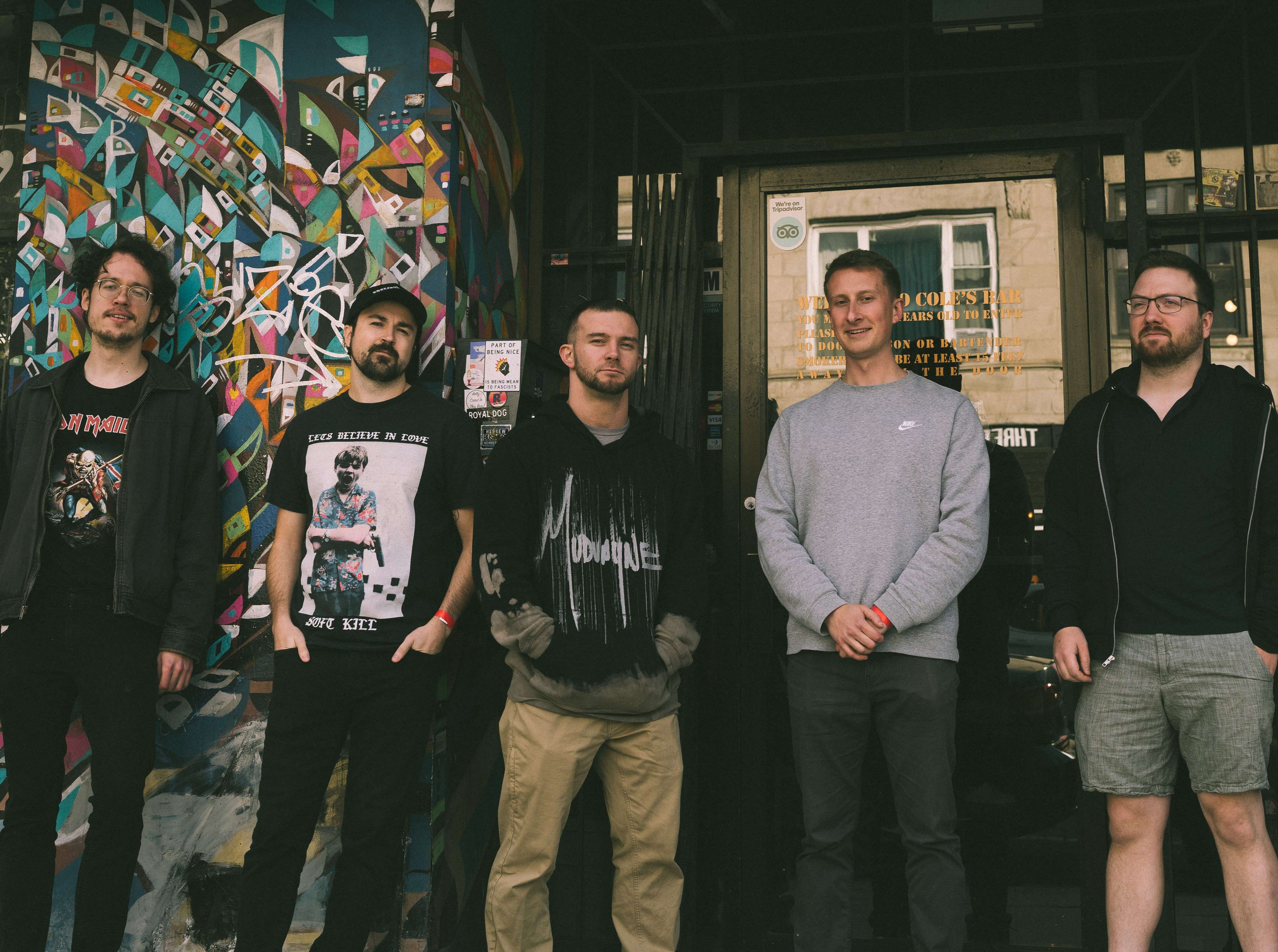 a group of men standing in front of a building with graffiti