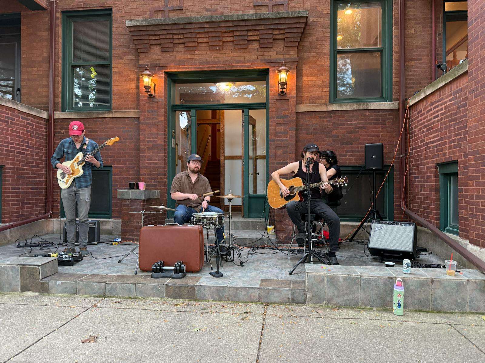 a group of people playing music in front of a brick building