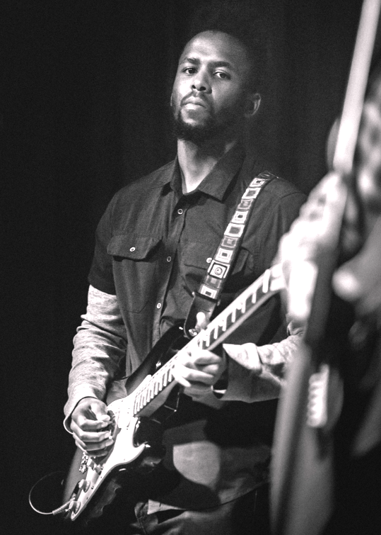 a black and white photo of a man playing an electric guitar