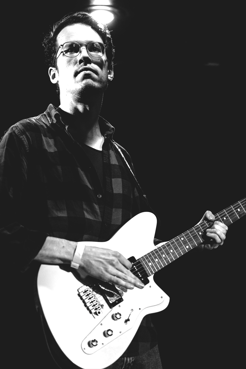 a black and white photo of a man playing an electric guitar