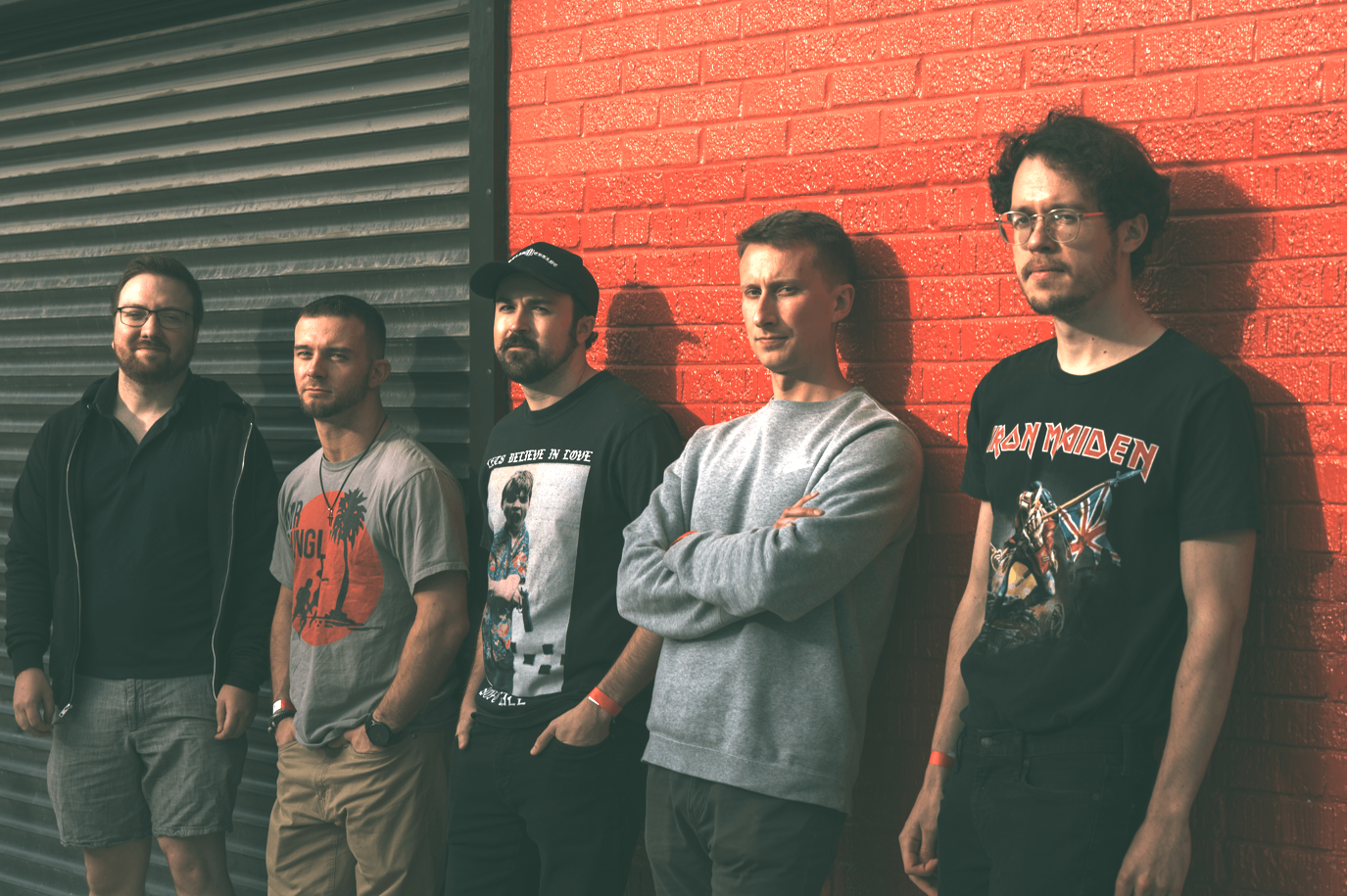 a group of men standing in front of a red brick wall