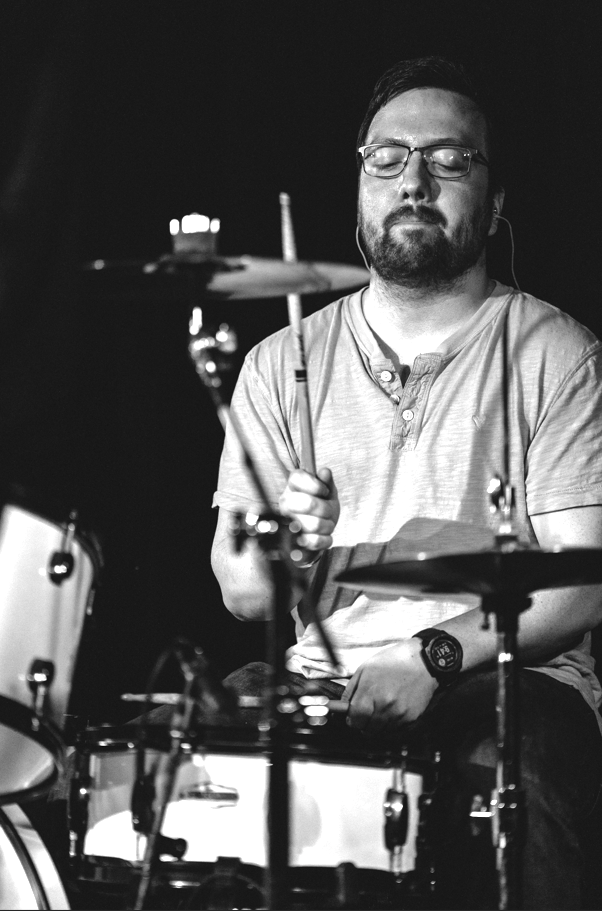a black and white photo of a man playing drums