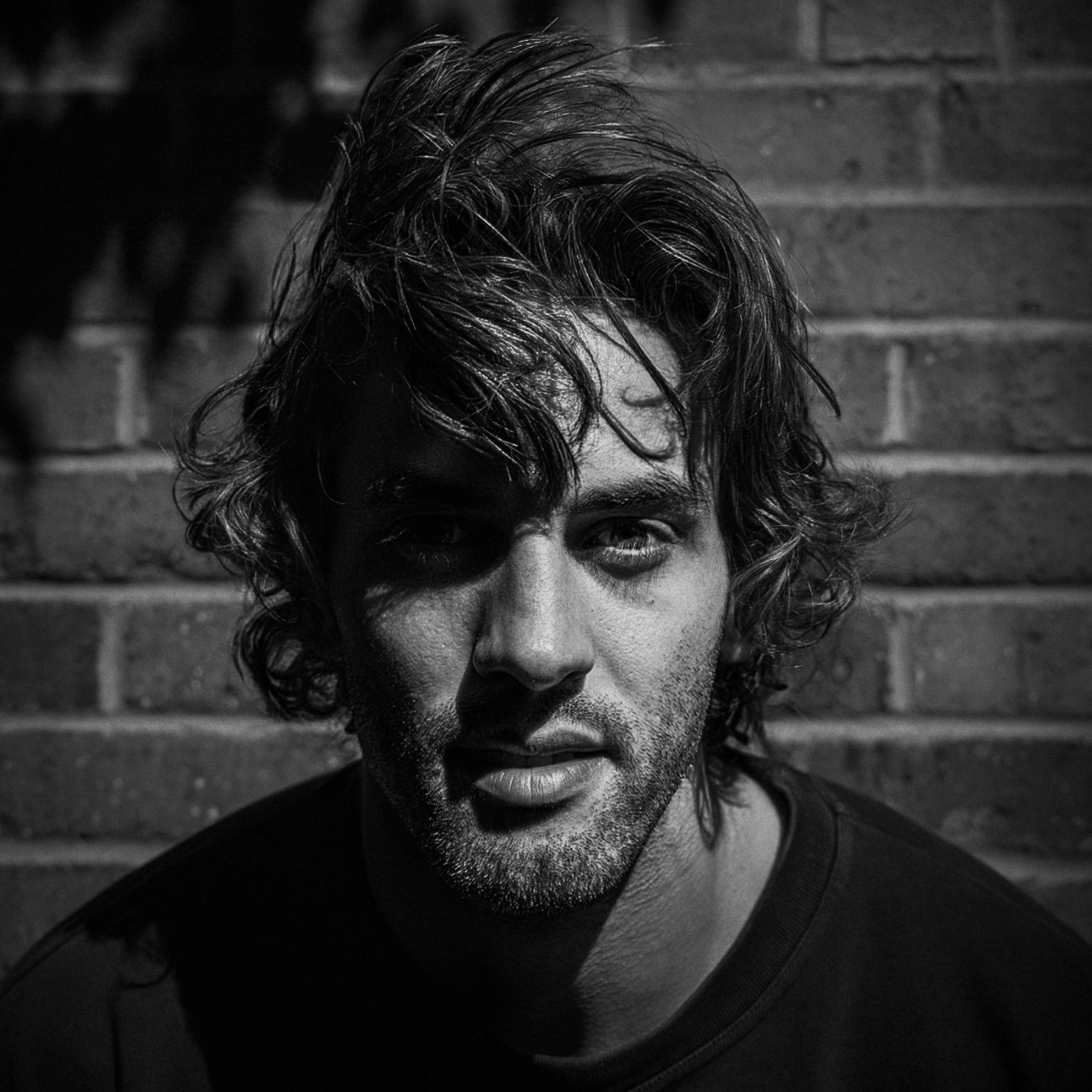 a black and white photo of a man in front of a brick wall