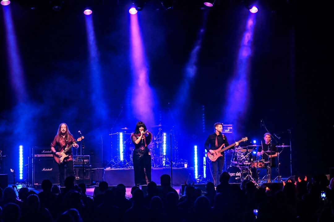 a group of people performing on stage in front of purple lights