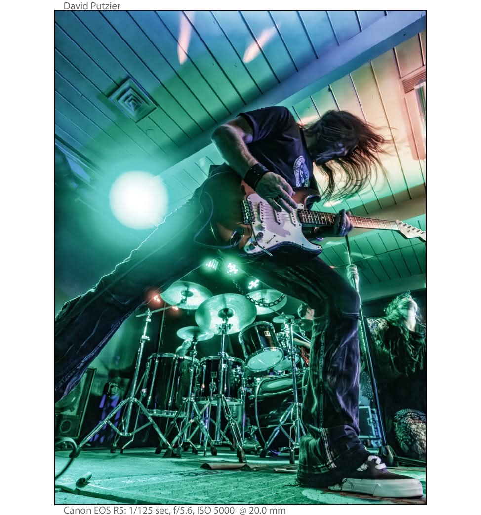 a man with long hair playing guitar on stage