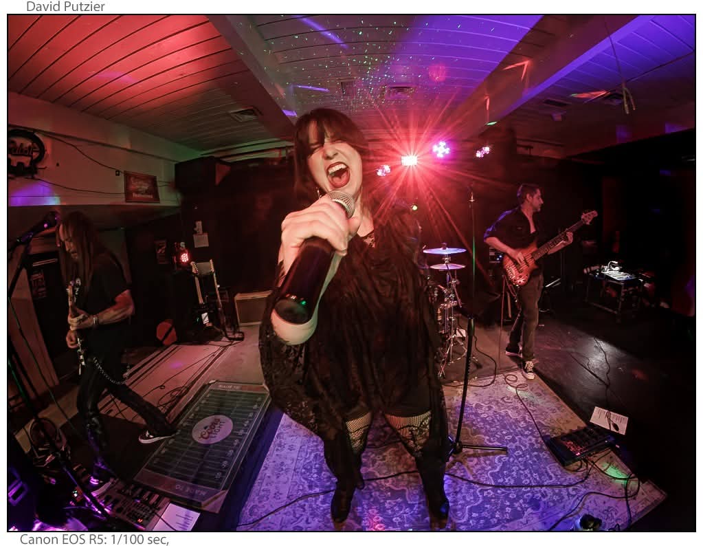 a woman singing into a microphone in a dark room