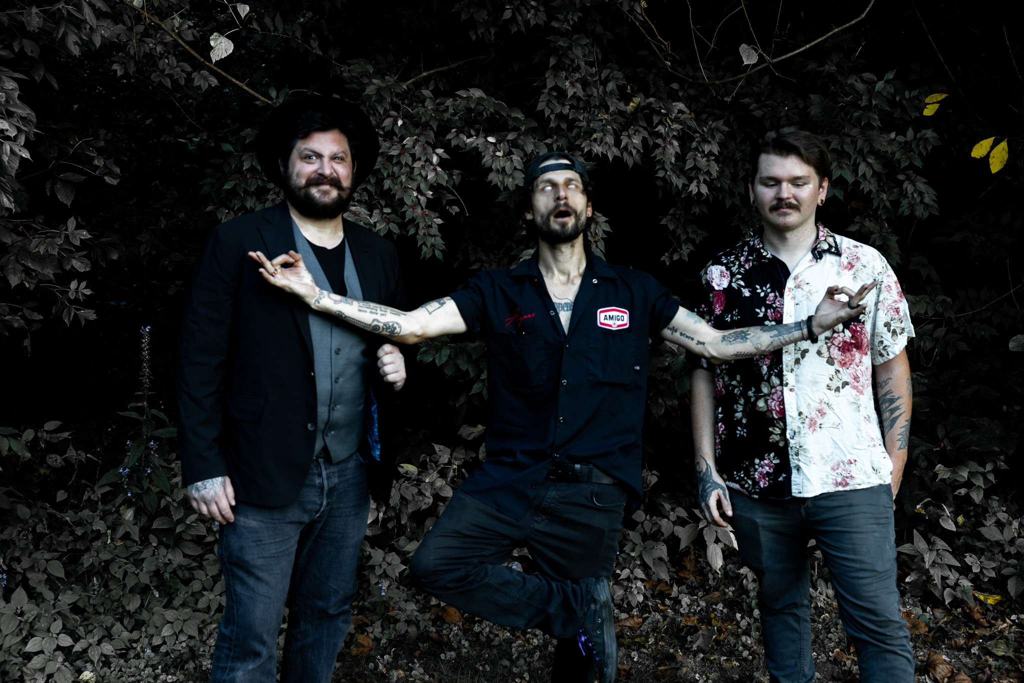 three men standing next to each other in the woods