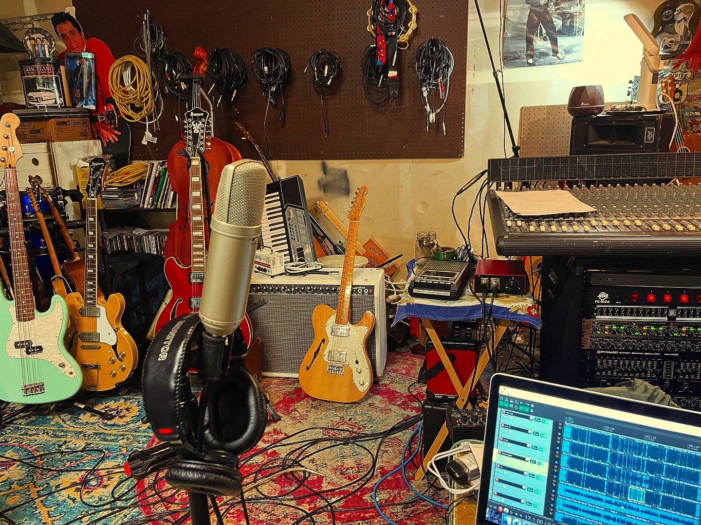 a recording studio with guitars, microphones, and a laptop