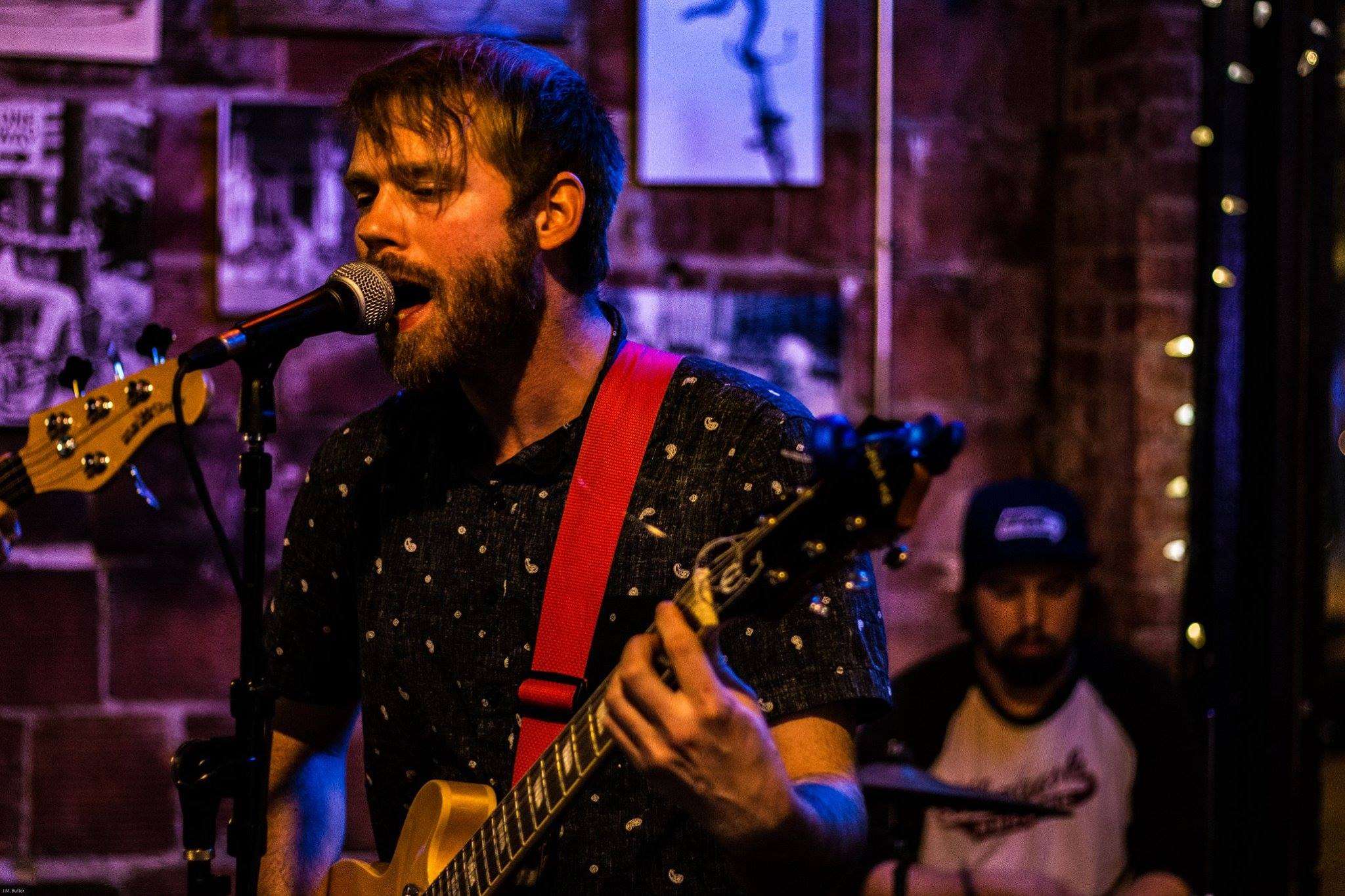 a man playing a guitar in front of a microphone