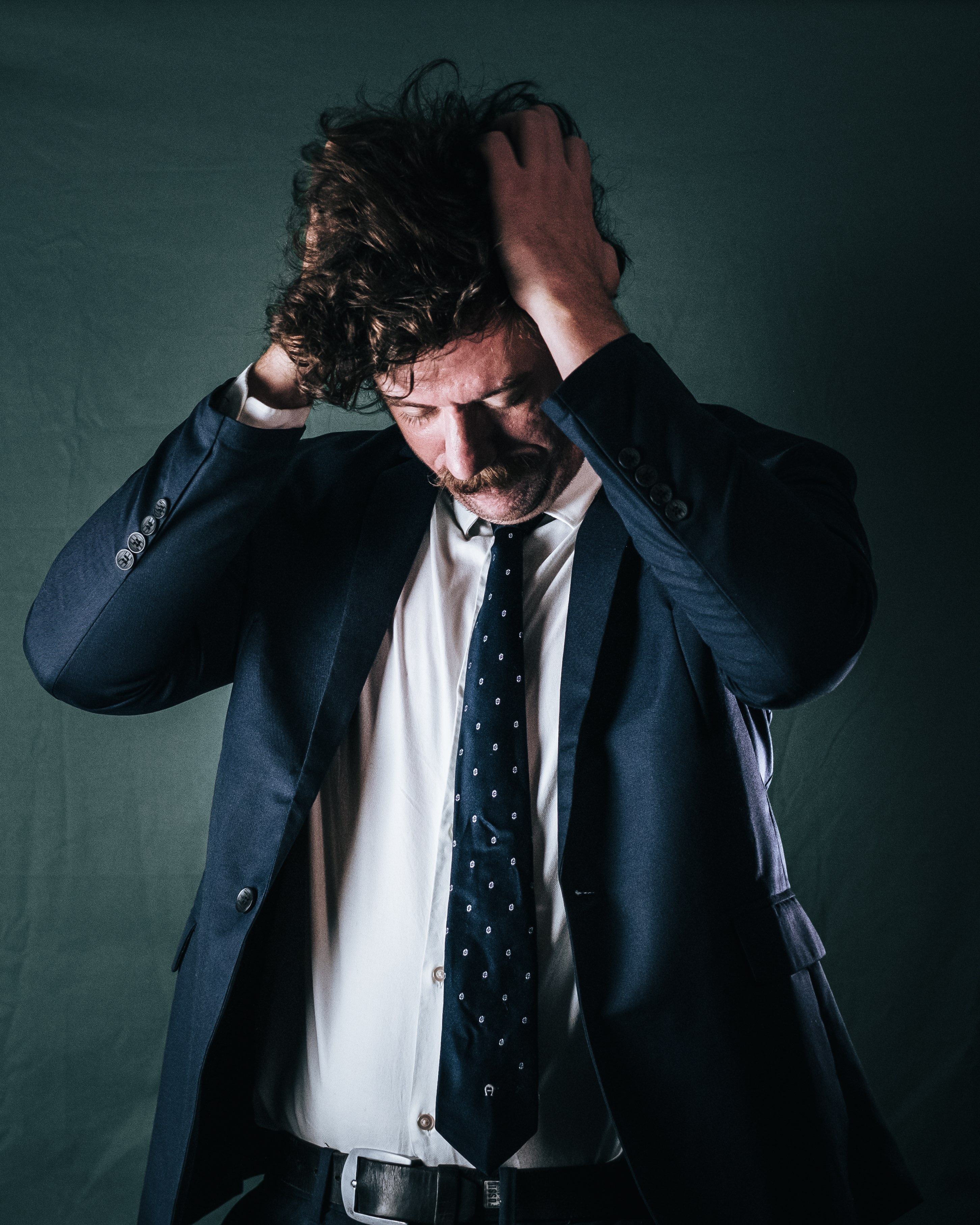 a man in a suit with his hands on his head