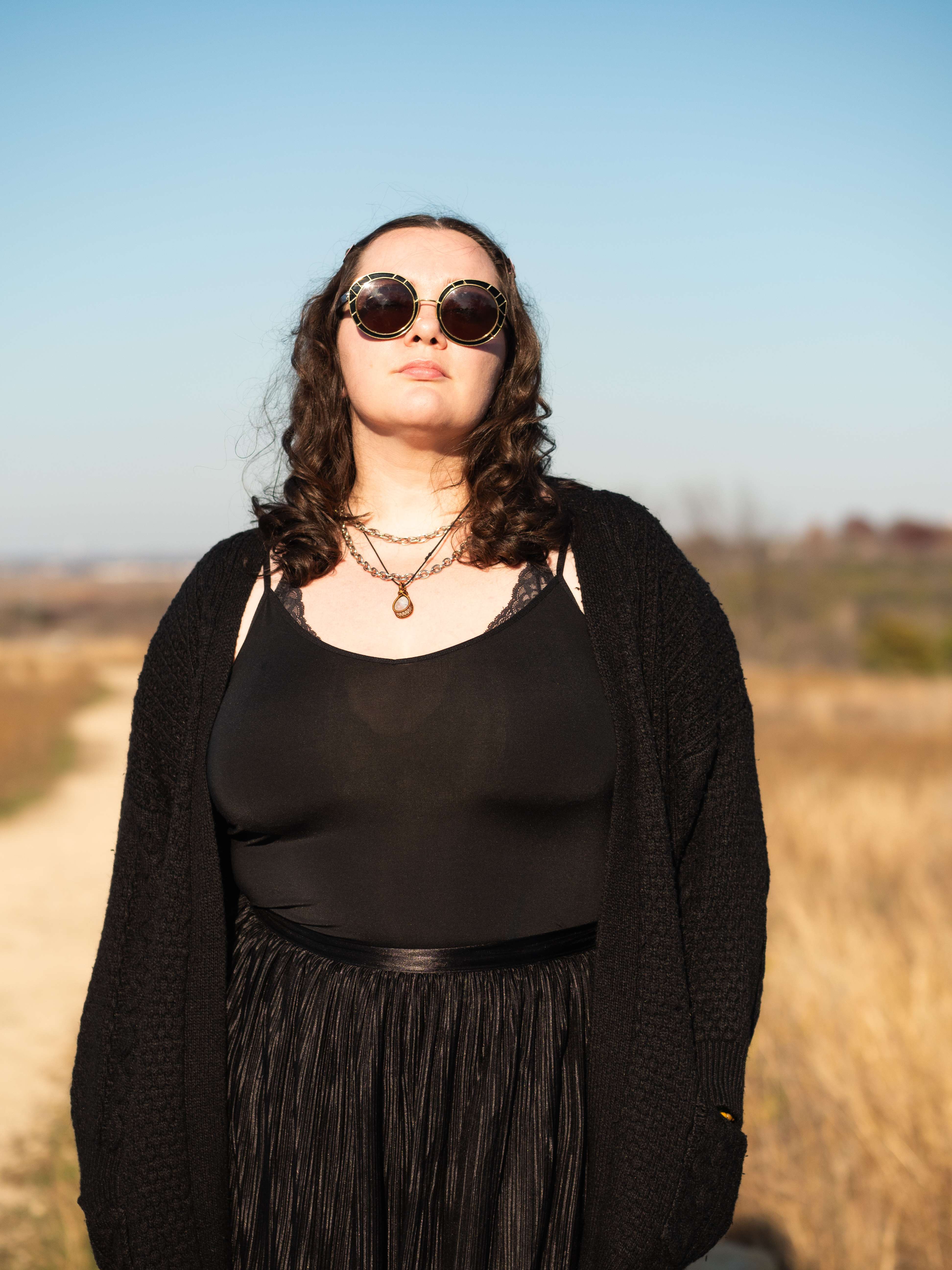 a woman in a black top and skirt standing in a field