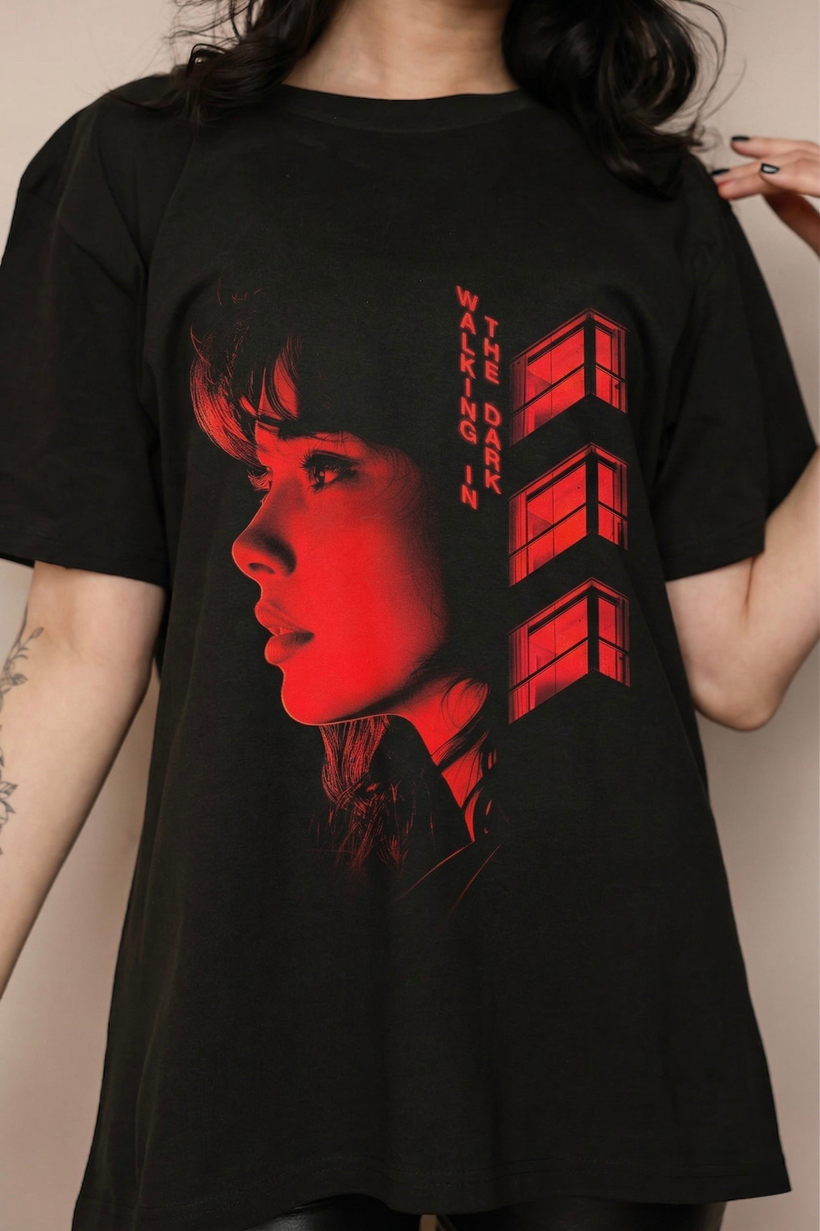 a woman wearing a black t - shirt with a red image of a woman