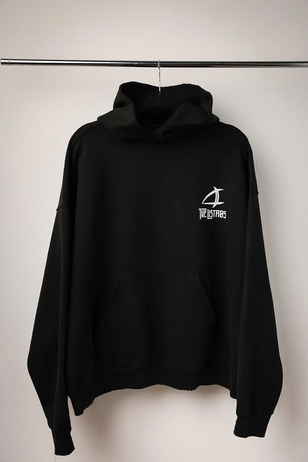a black hoodie with a white logo hanging on a hanger
