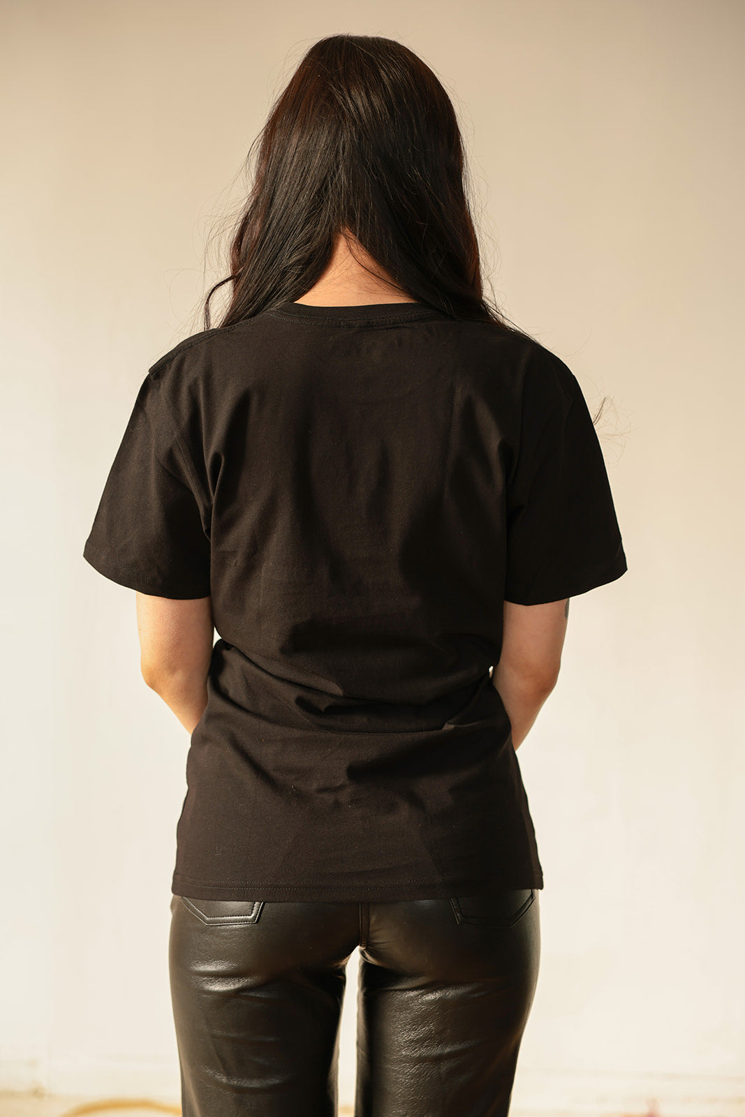 the back of a woman wearing leather pants and a black t - shirt