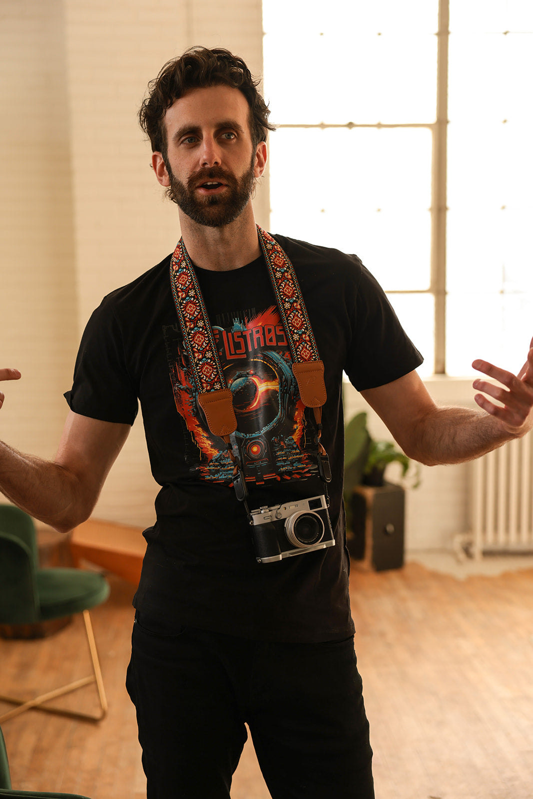 a man standing in a room with a camera strap